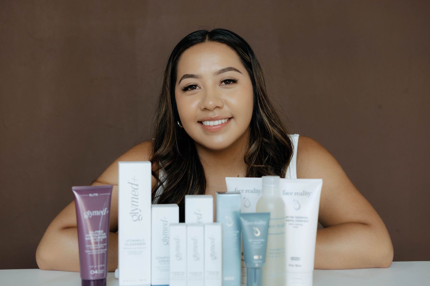 Display of various skincare products arranged on brown surface.