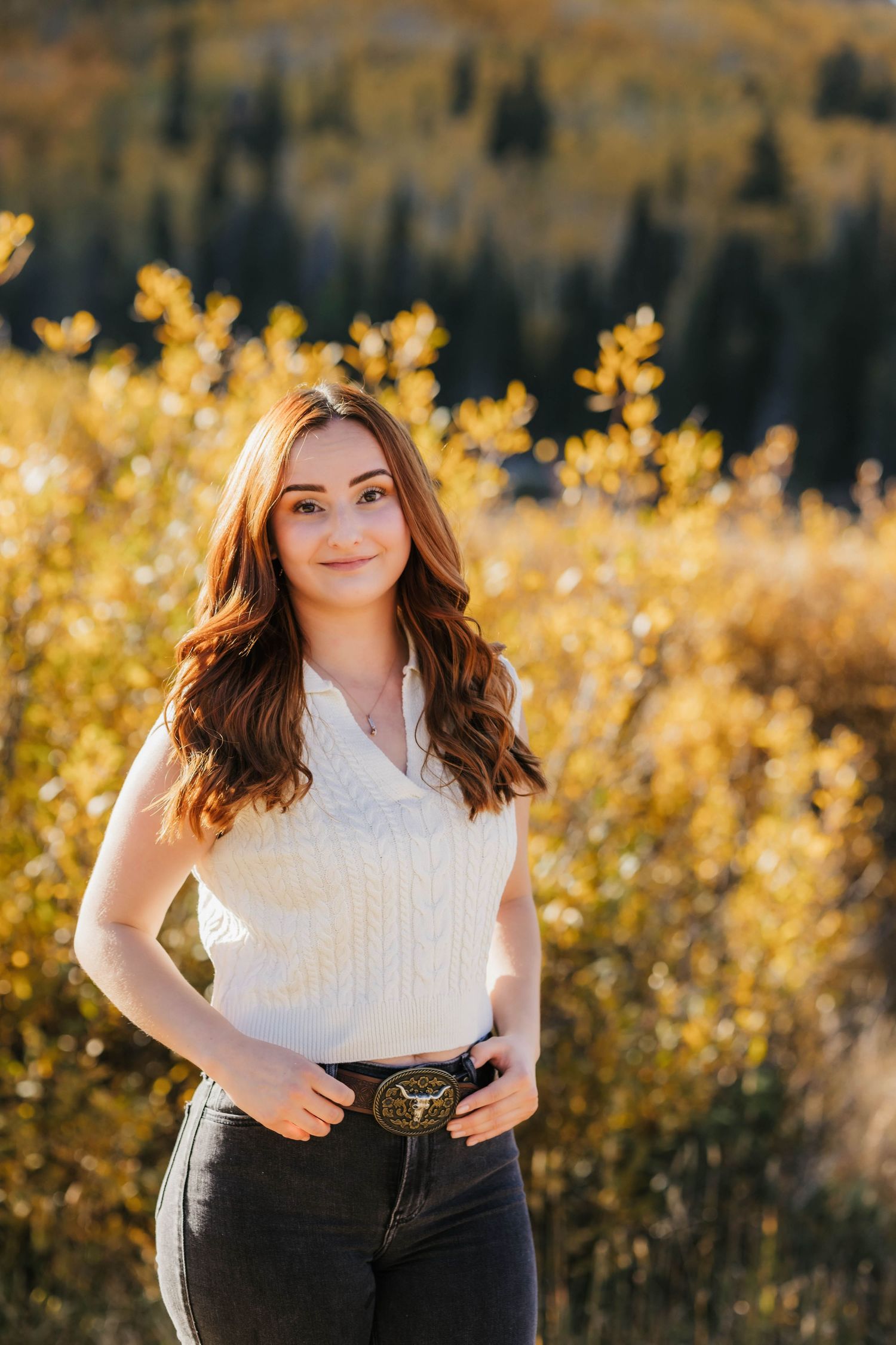 Portrait in a natural outdoor setting with golden autumn foliage in the background.
