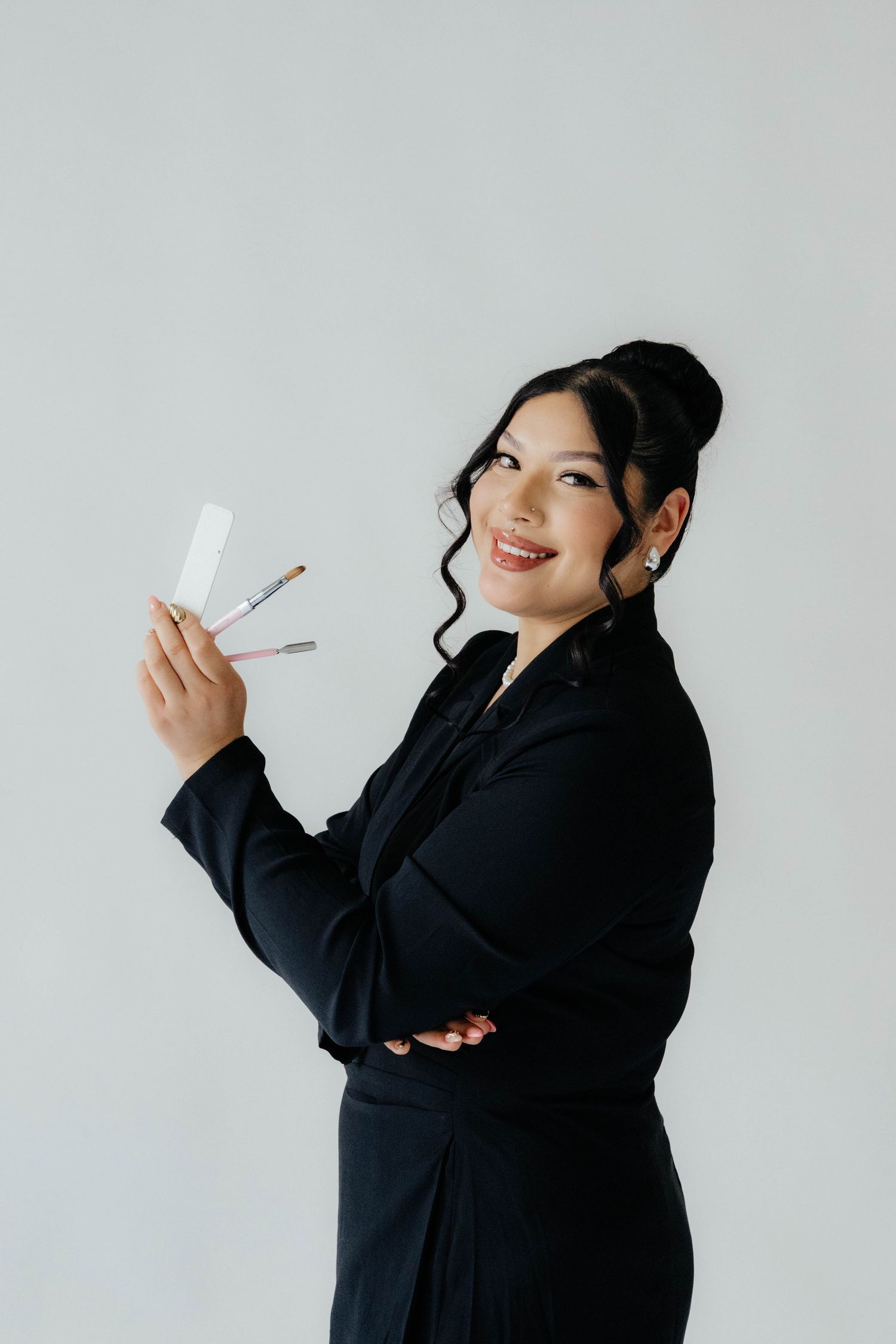 Person in black attire posing playfully against a light gray studio backdrop.