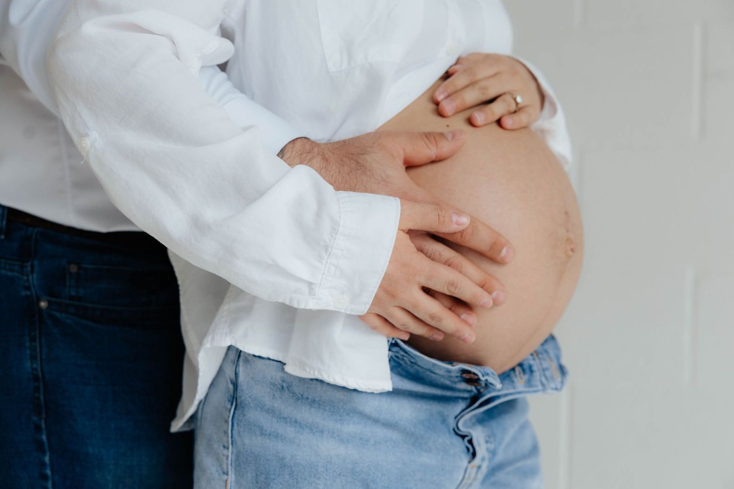 Close-up shots of a pregnant belly with hands gently cradling it.
