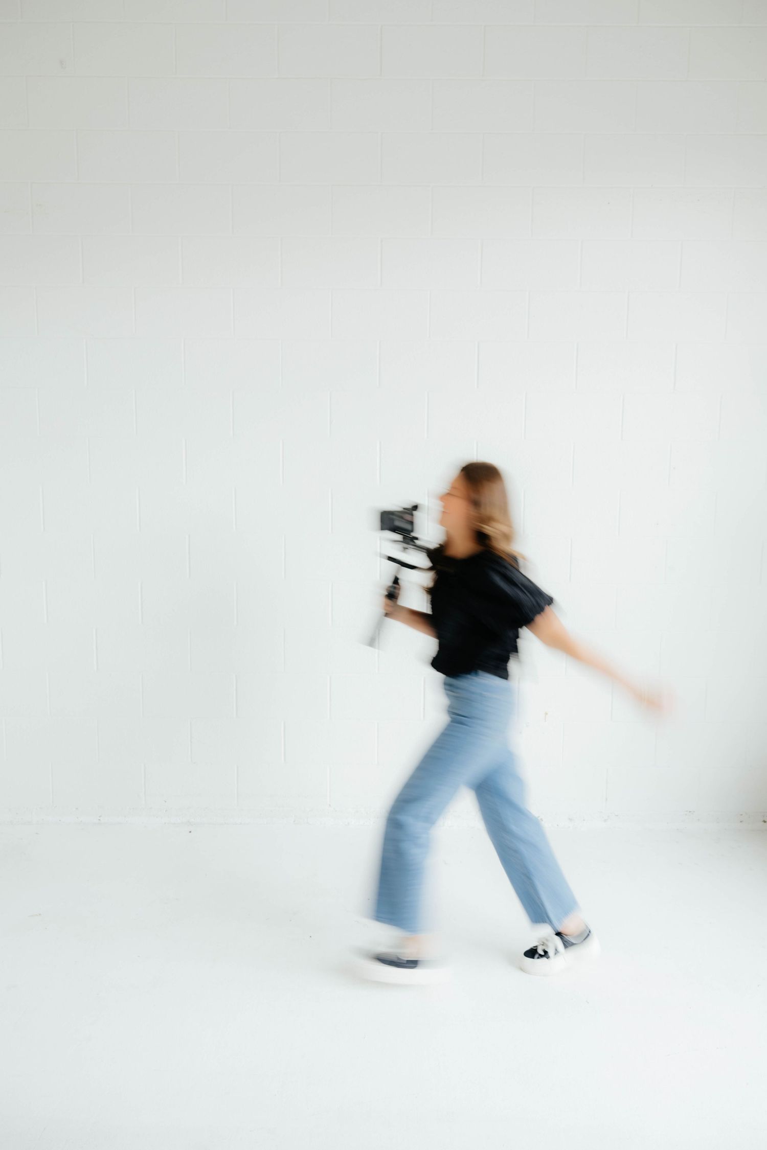 Motion blur sequence of someone moving with camera equipment against white background.