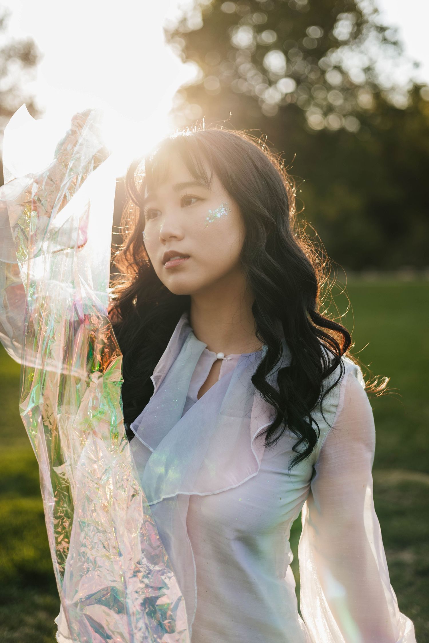 A dreamy backlit portrait in a white blouse with ethereal sunlight creating a glowing effect.