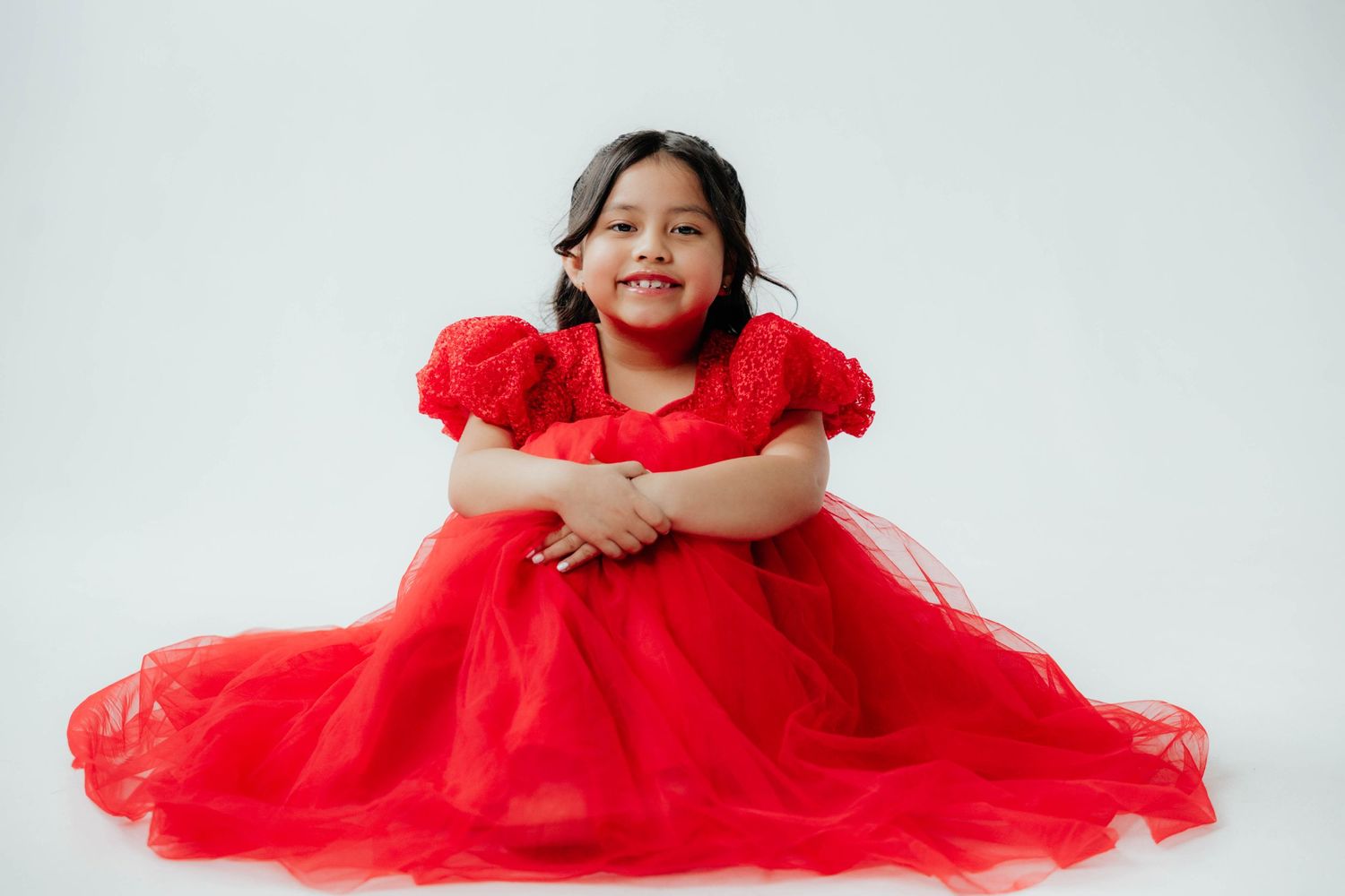 A portrait session featuring a red tulle dress against a clean white background.