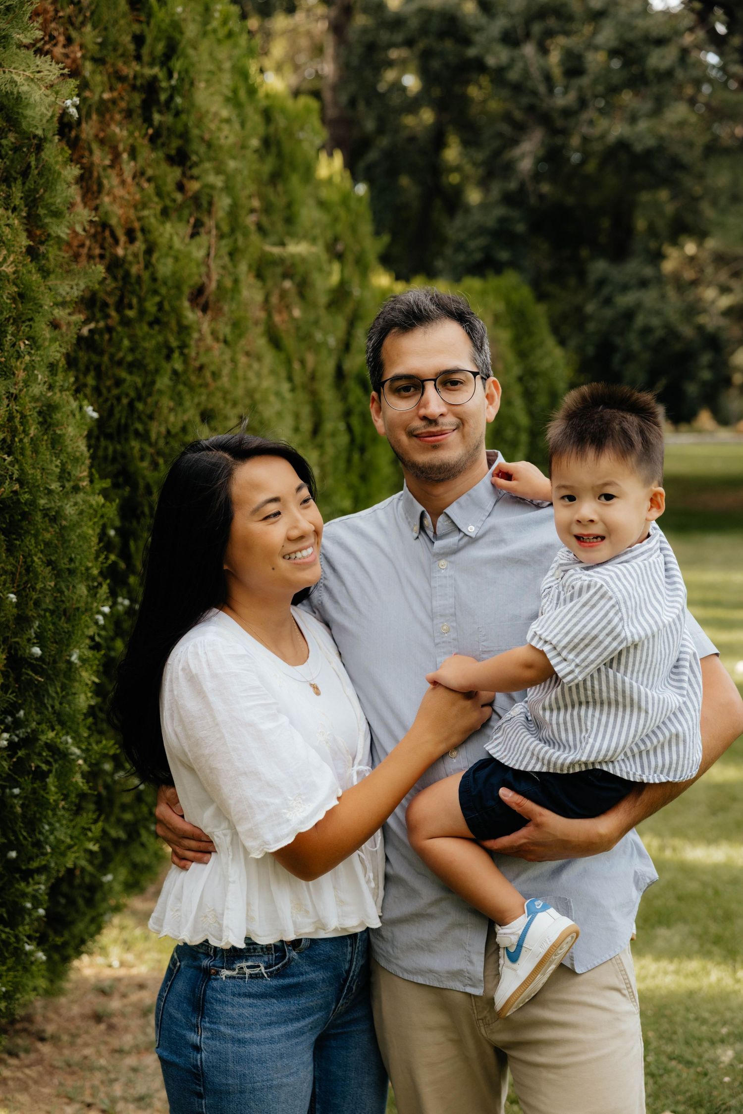 Casual family portrait session outdoors with everyone wearing coordinated neutral outfits.