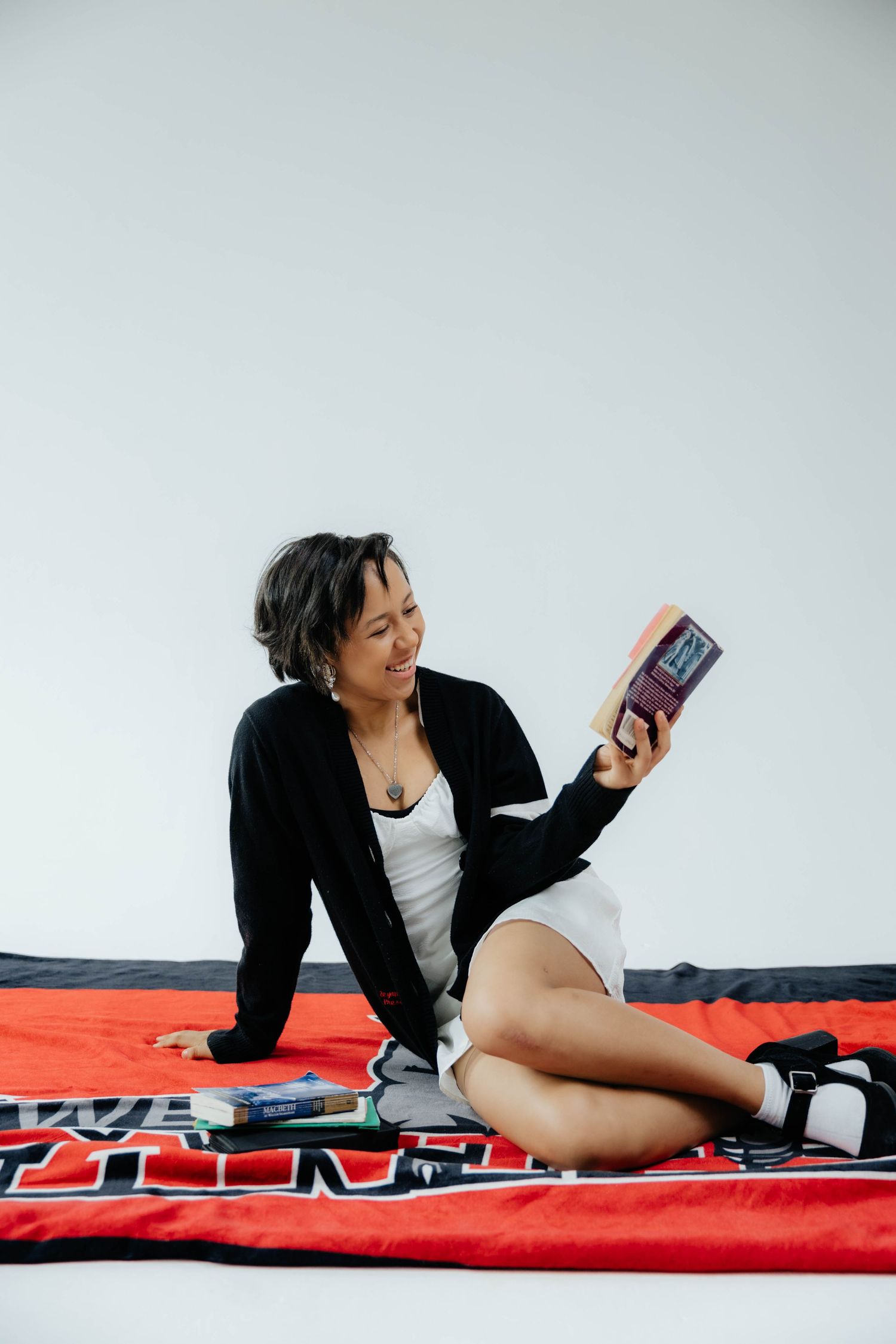 Casual lifestyle photos of someone reading and relaxing on a red patterned blanket.
