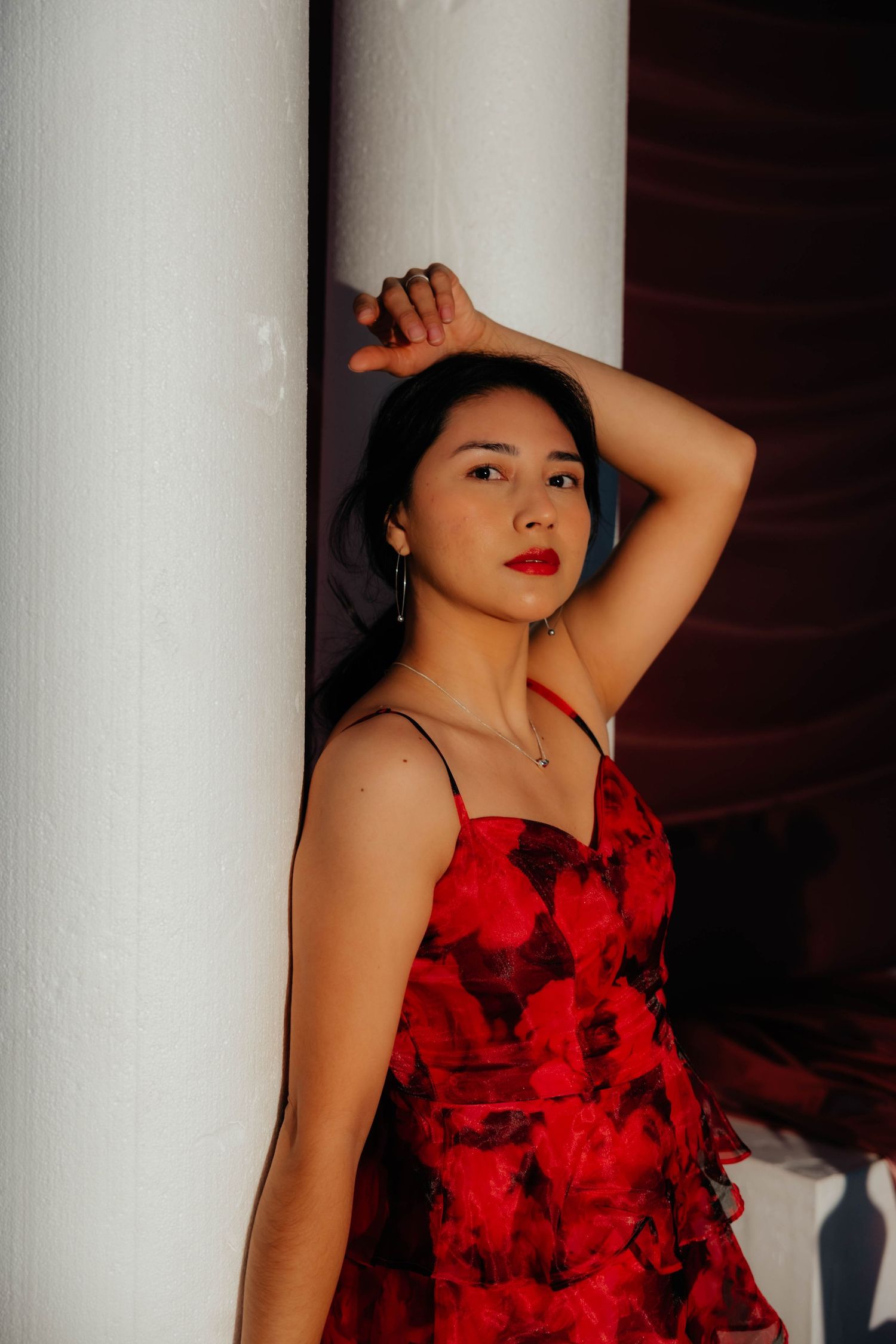 Portrait series between white columns featuring red dress and dramatic lighting.
