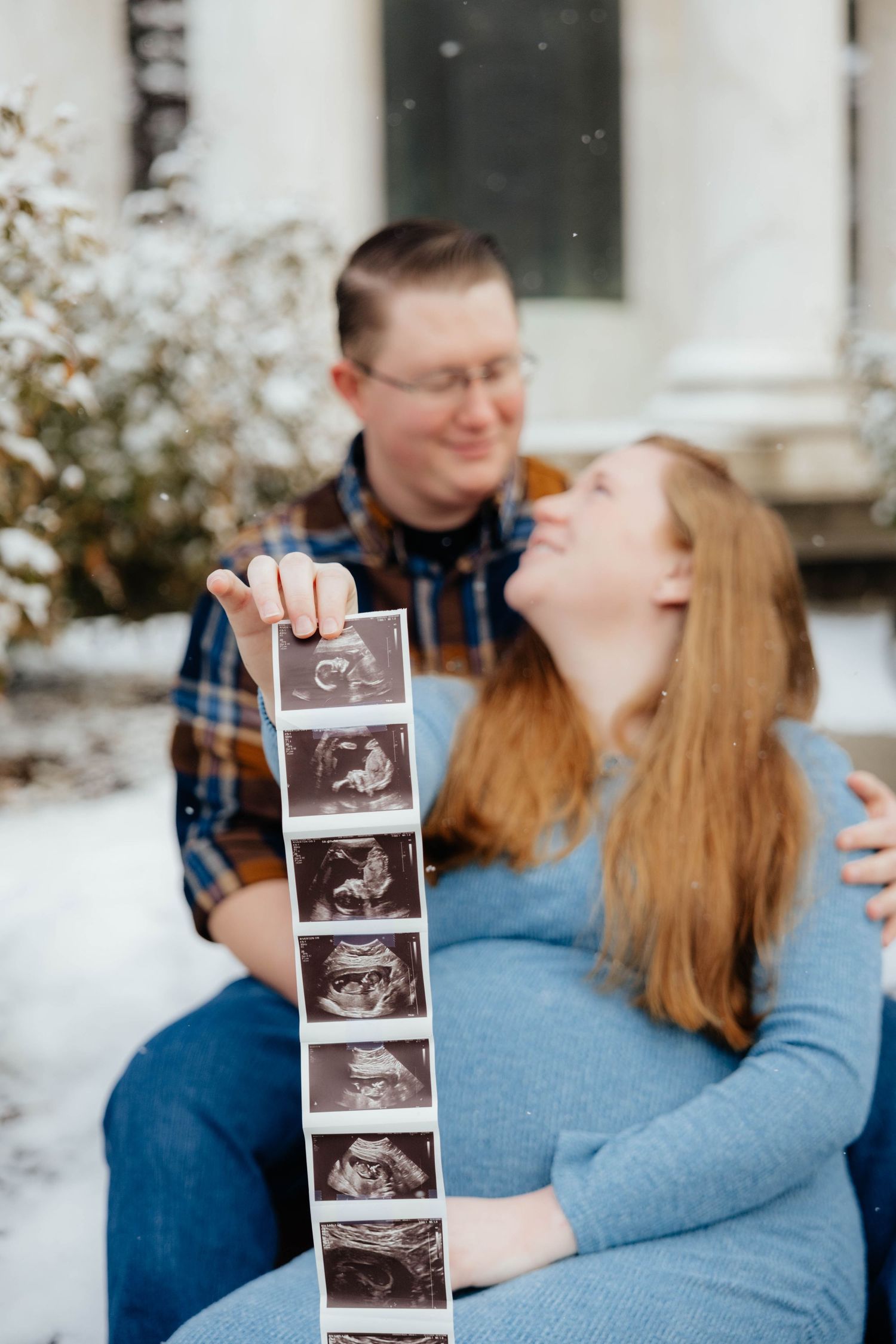 Couple holding ultrasound photos while sharing joyful moment together.