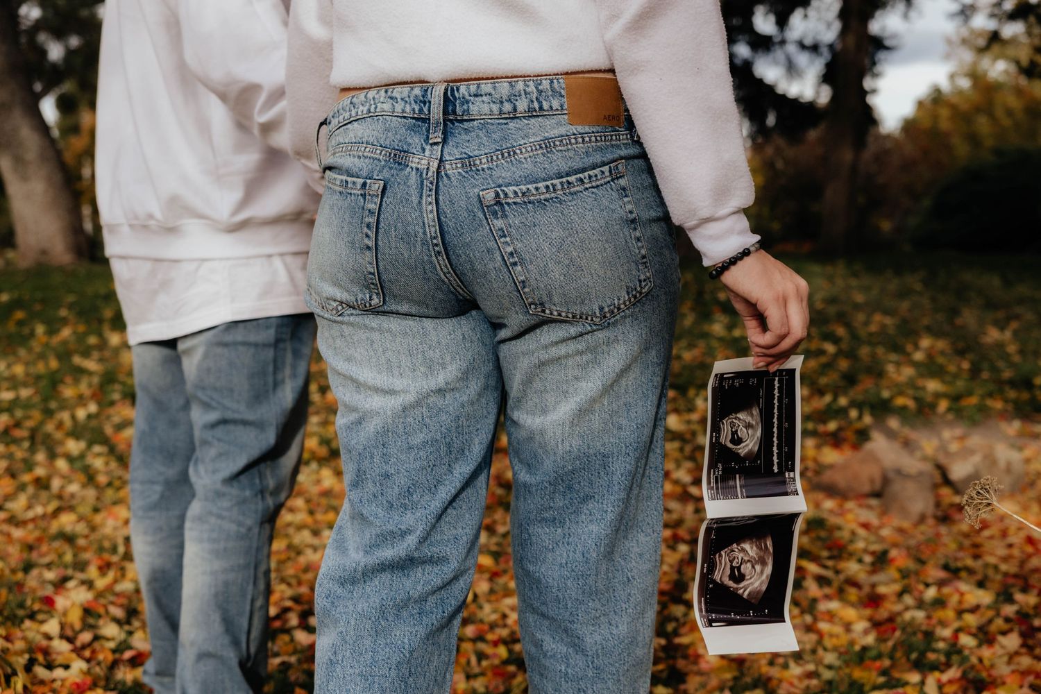 Series of maternity photos showing ultrasound images held against denim.