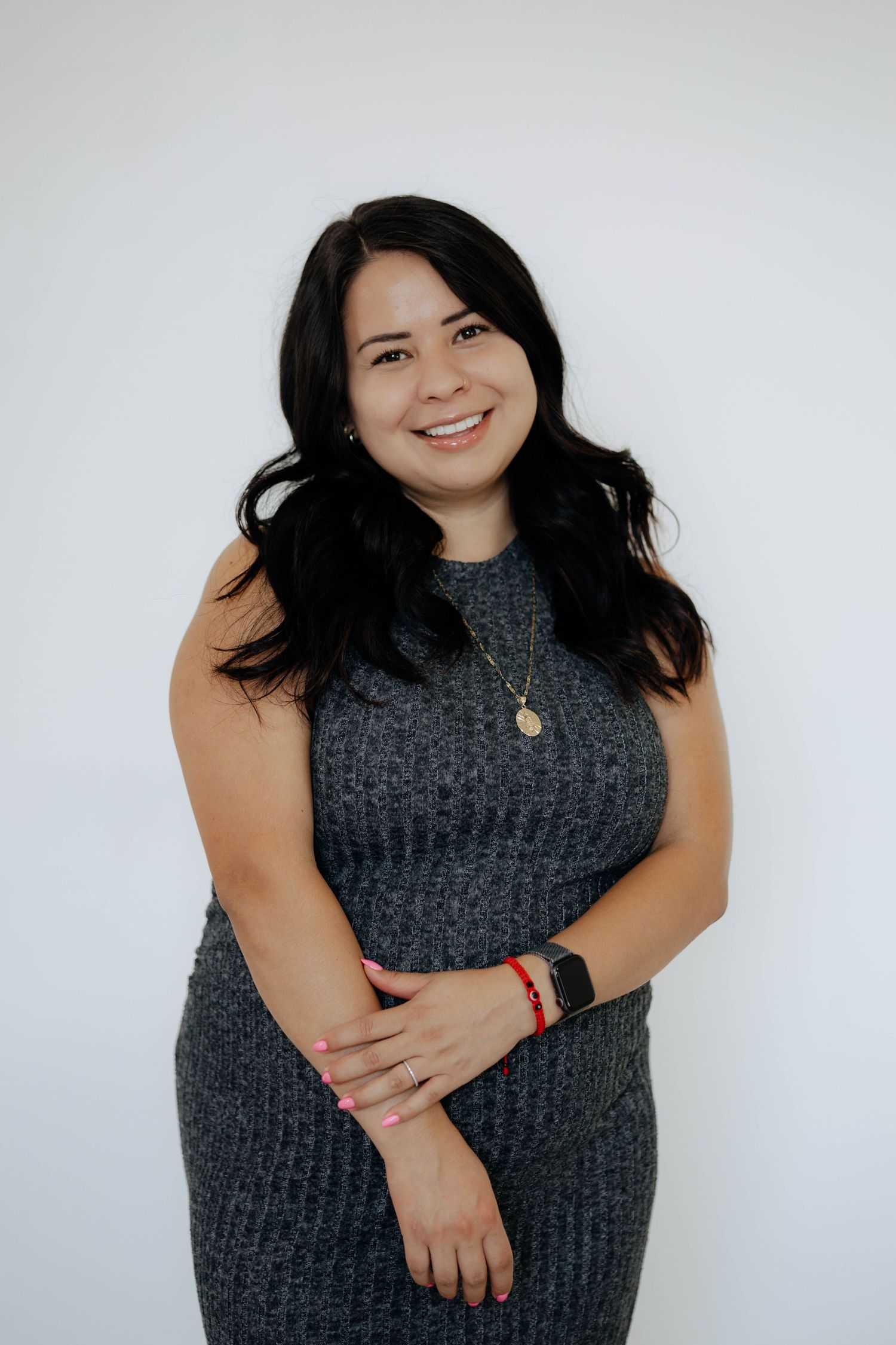 Person in a grey sleeveless sweater poses against white background.