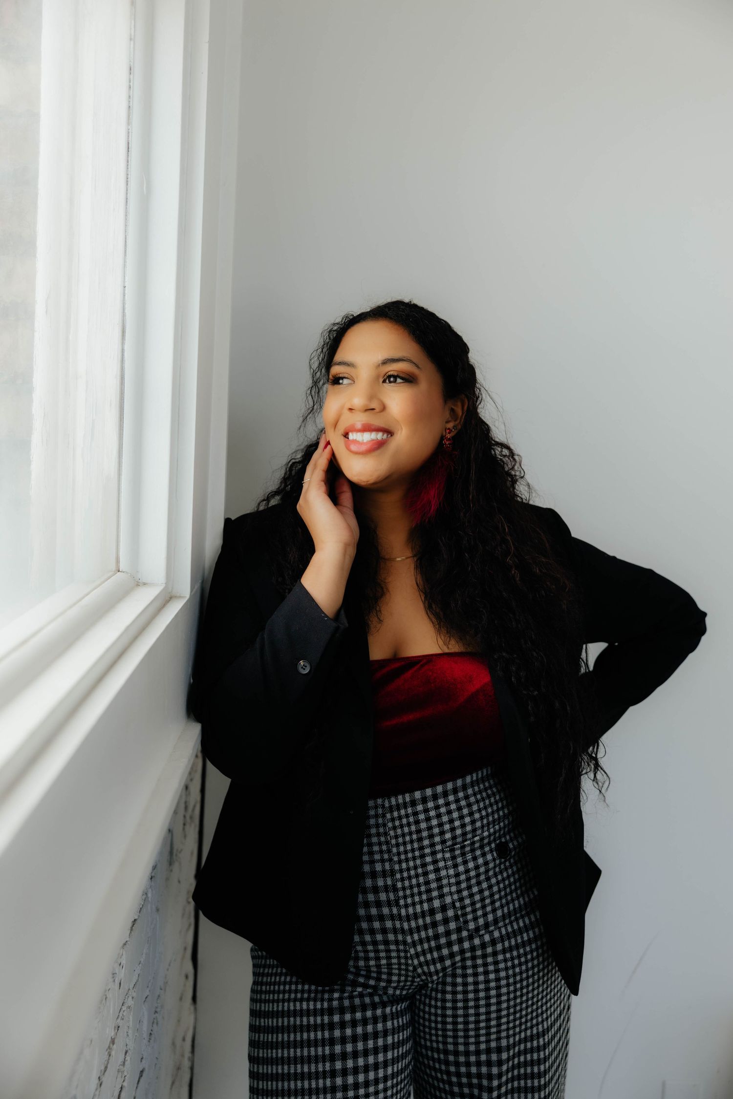 Indoor portrait session by a window featuring casual black attire and natural lighting.