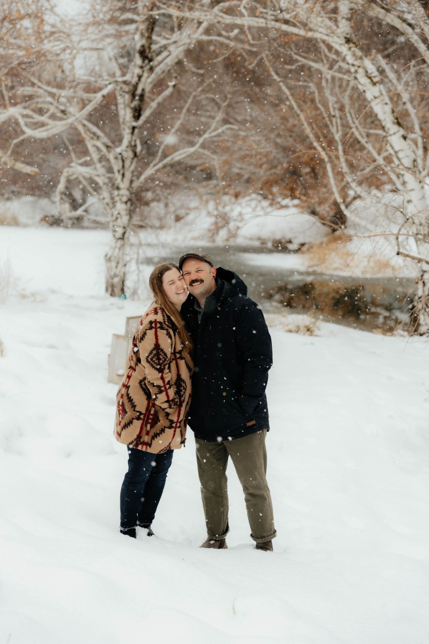 Couple in winter clothing sharing intimate moment in snowy landscape.