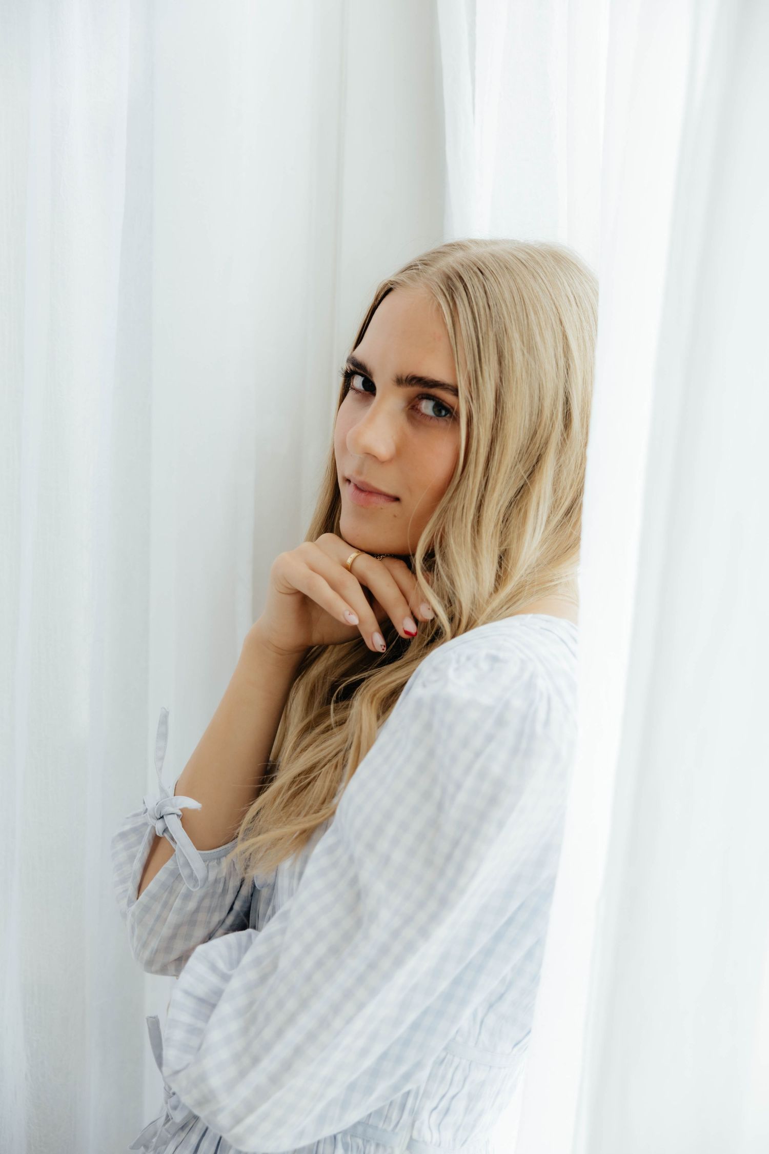 Soft dreamy portraits against white curtains in natural window light.