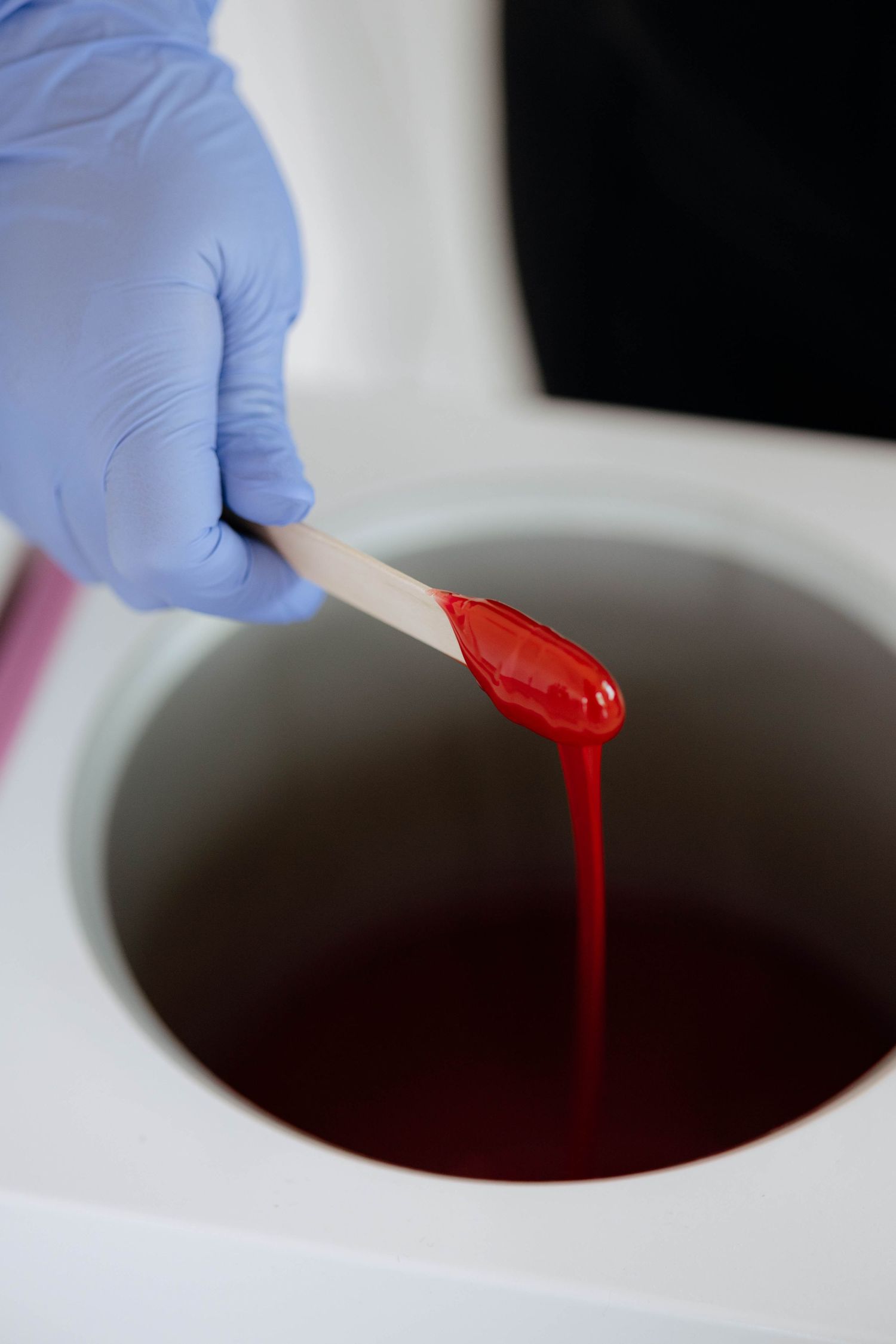 Close-up sequence showing red liquid being dropped into a dark liquid in a bowl.