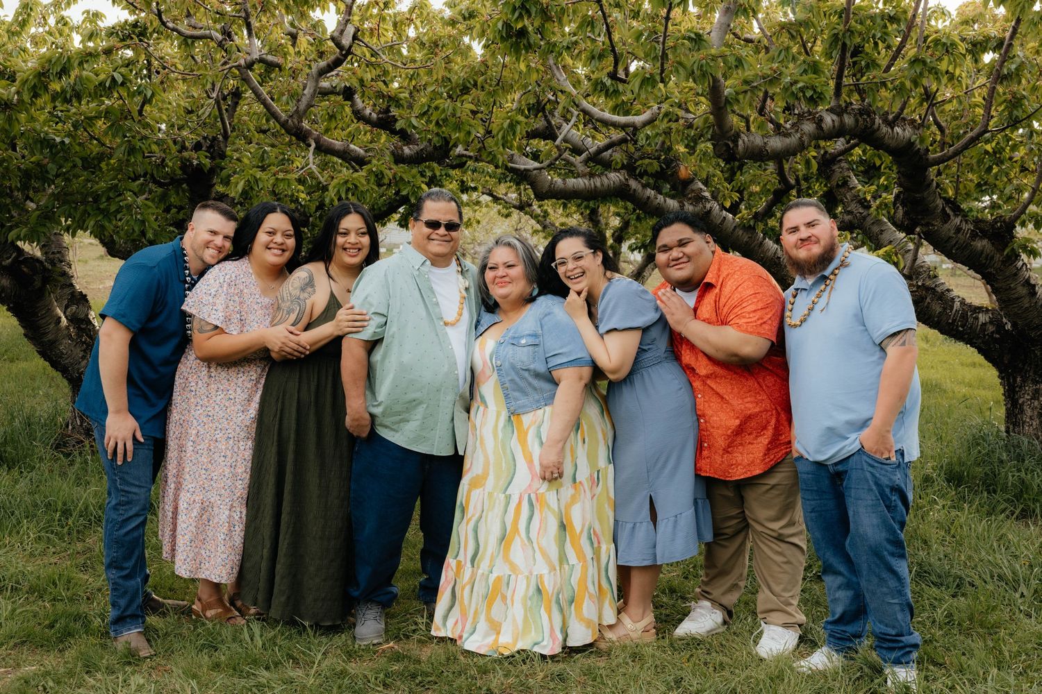 Extended family portrait session in a sunny garden setting with natural poses.