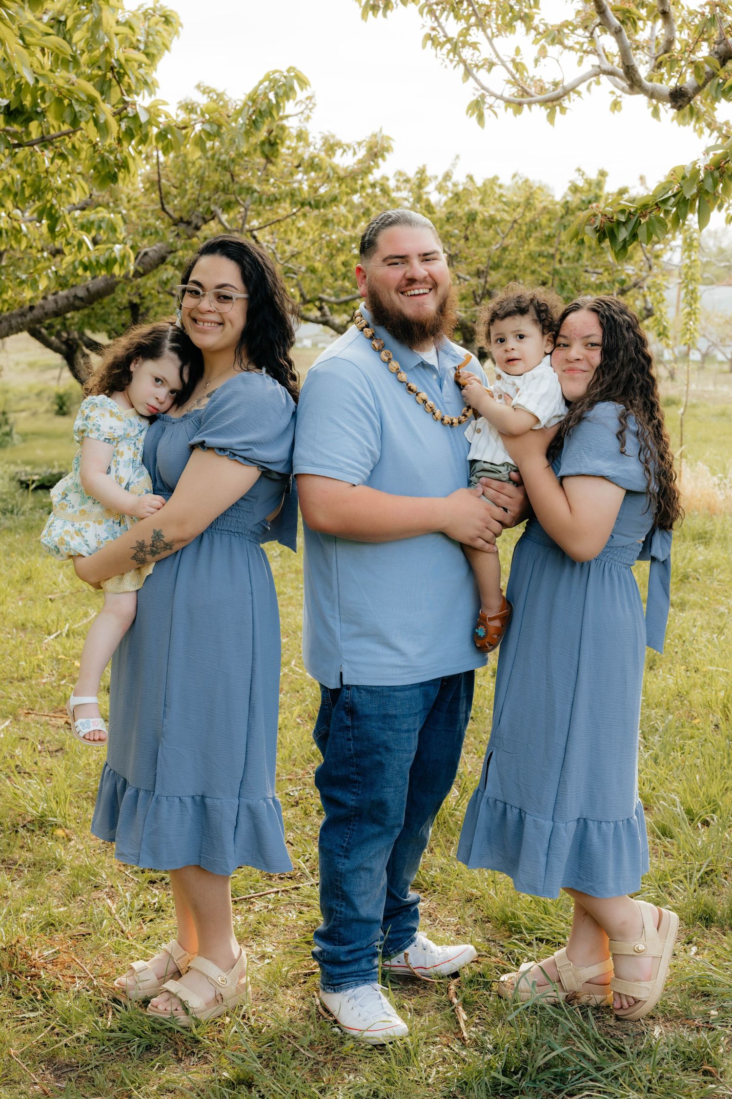 Family group photos in coordinating blue outfits against a sunny outdoor backdrop.