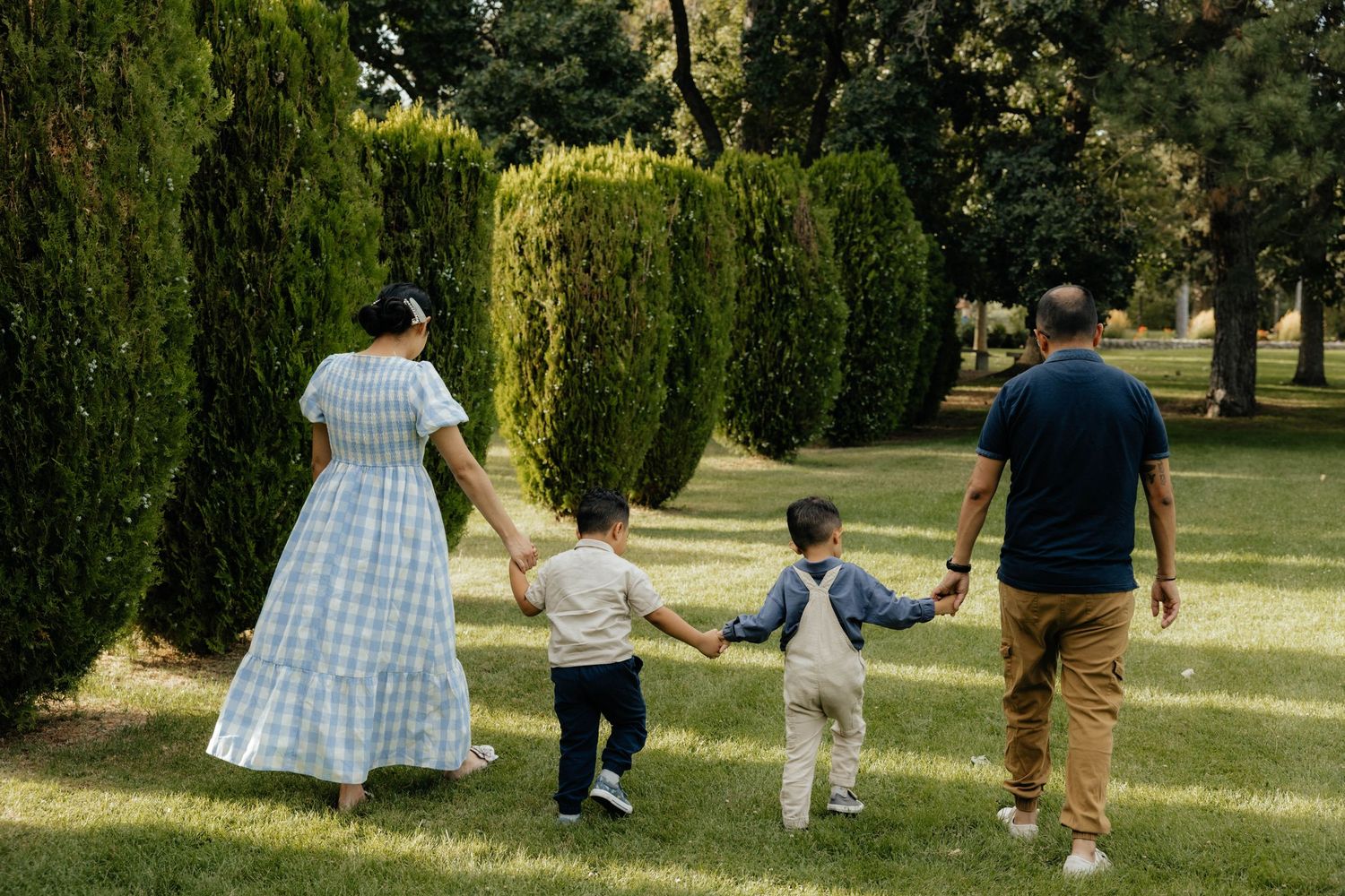 A family walking together through a sunlit park with trees in the background.