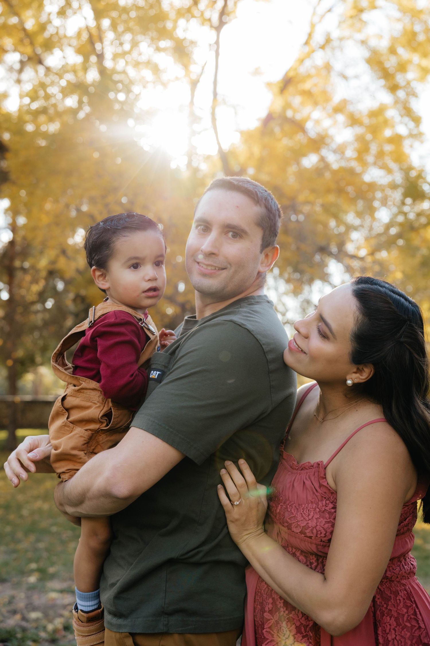 Joyful family moment captured outdoors with golden autumn sunlight filtering through trees.