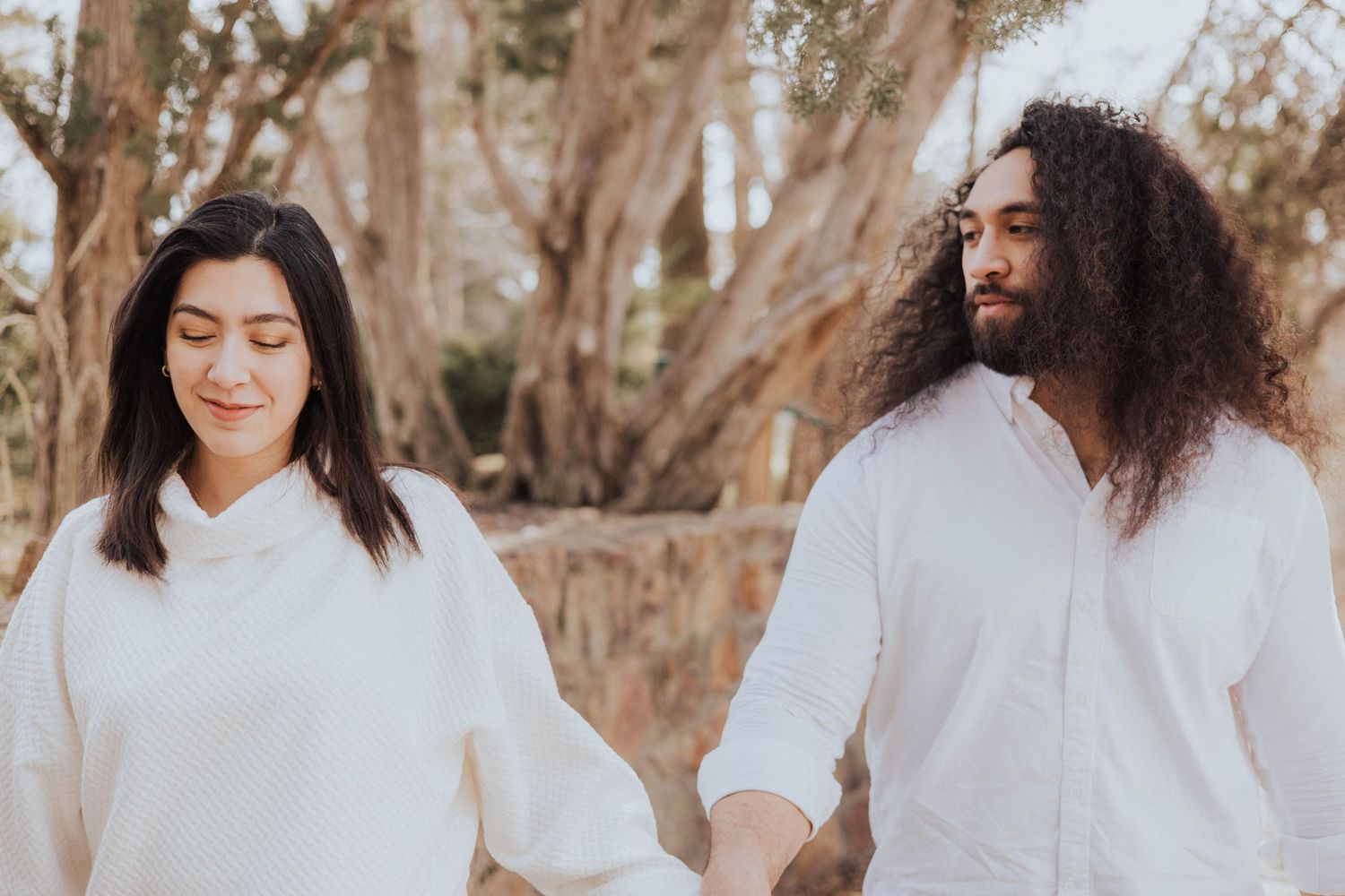Couple in white clothing sharing tender moments in natural setting.