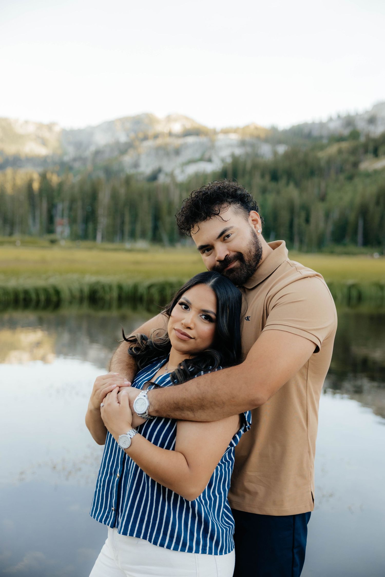 Affectionate couple sharing tender moments by serene mountain lake.