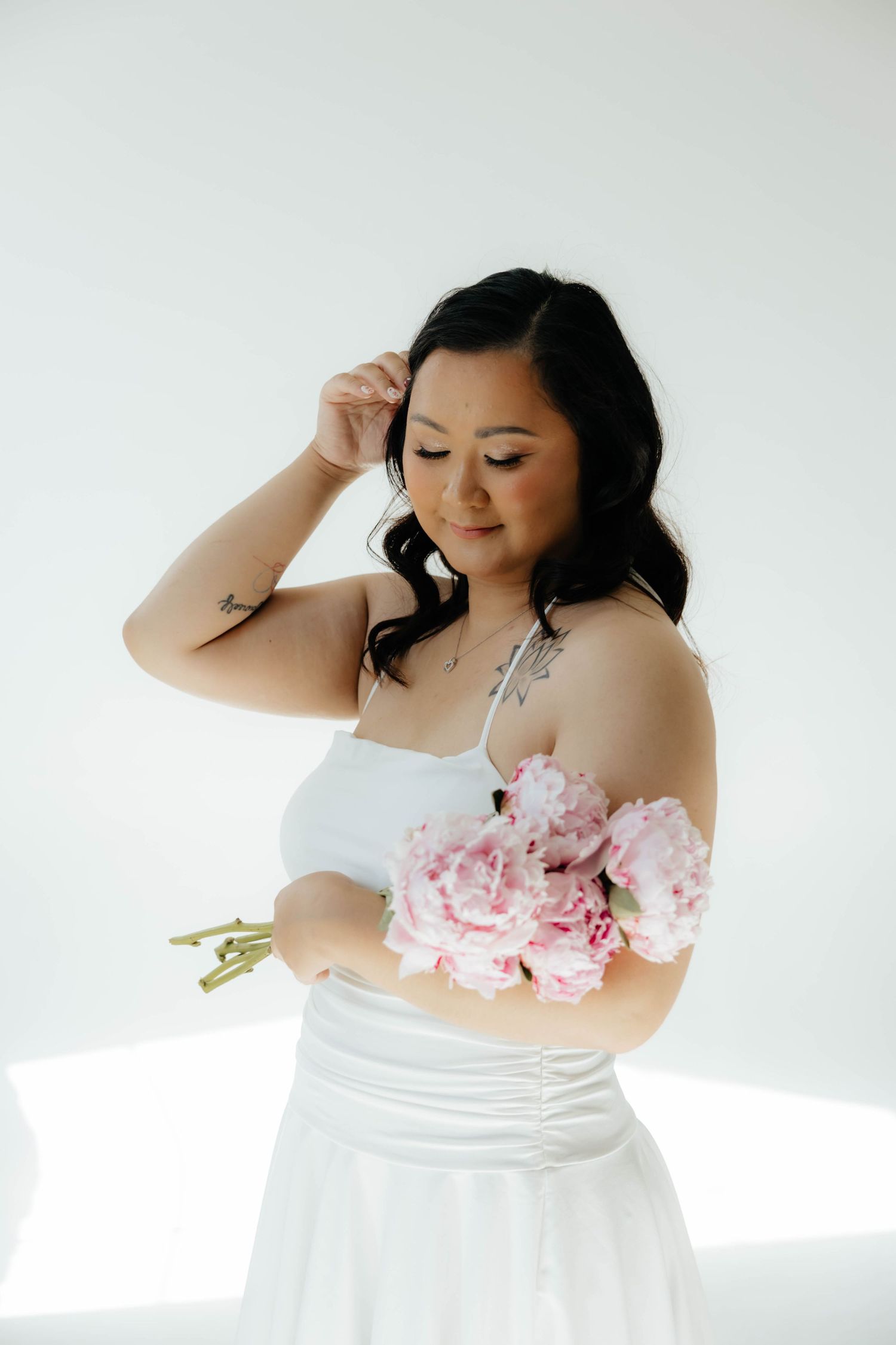 Studio portrait featuring a white dress and pink peonies against a minimalist white background.