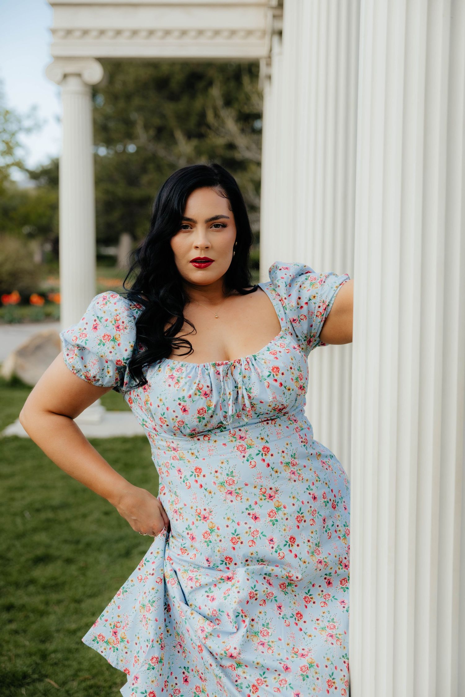 Light blue floral dress photographed against classical white columns in an outdoor setting.