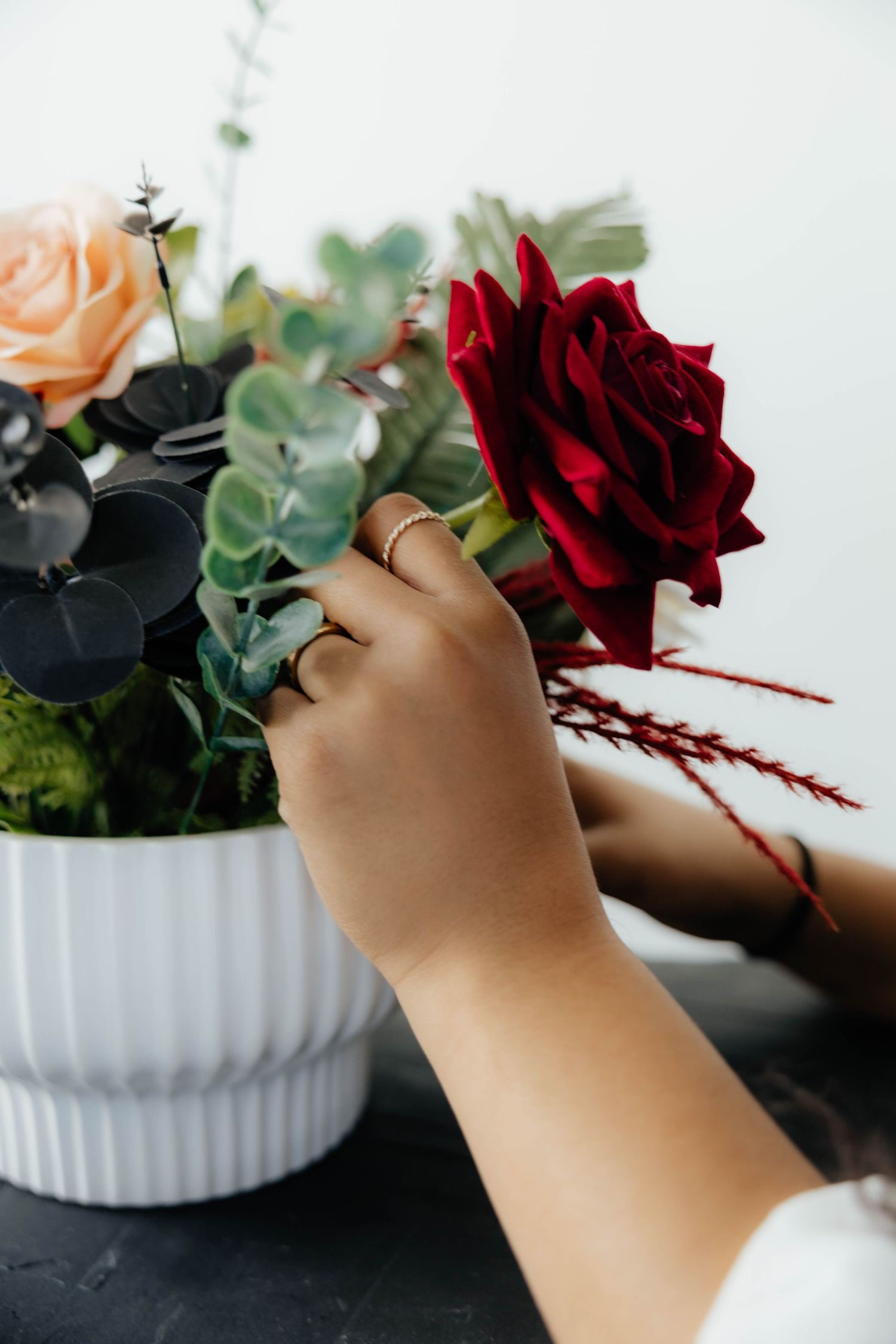 Arranging flowers in white vases with red roses and peach blooms.