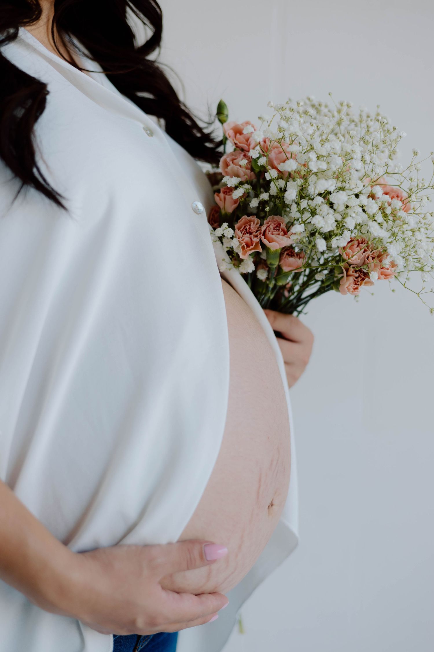 Maternity portrait with delicate flowers and a white flowing top.