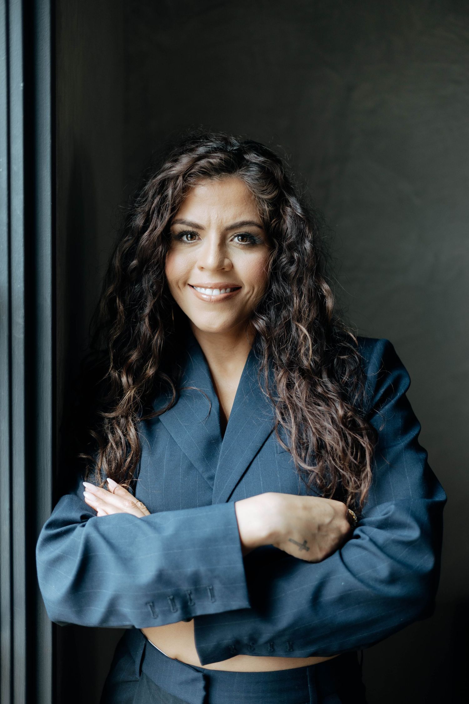 Studio portrait against dark background wearing navy blue clothing.