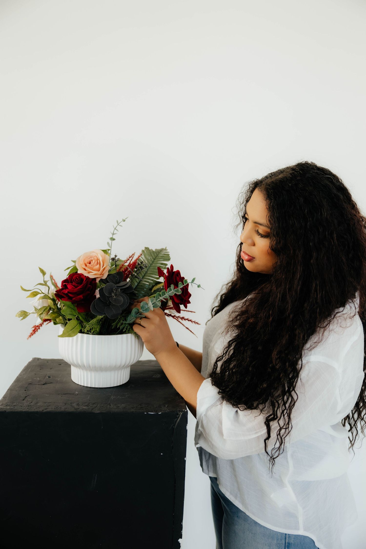 A series of photos showing someone arranging floral displays with roses and greenery on a black surface.