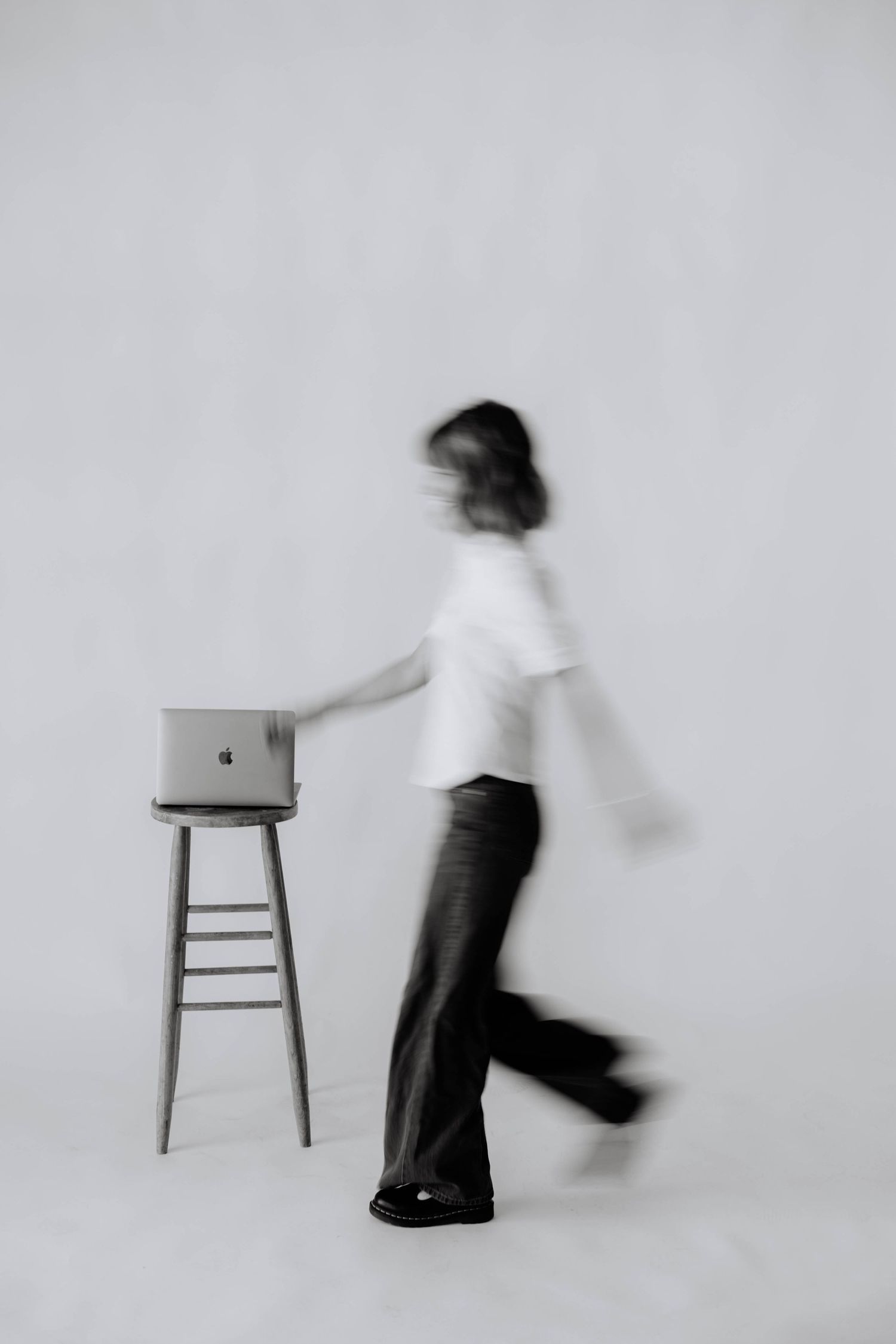 Minimalist motion blur photography sequence with person and chair against white background.
