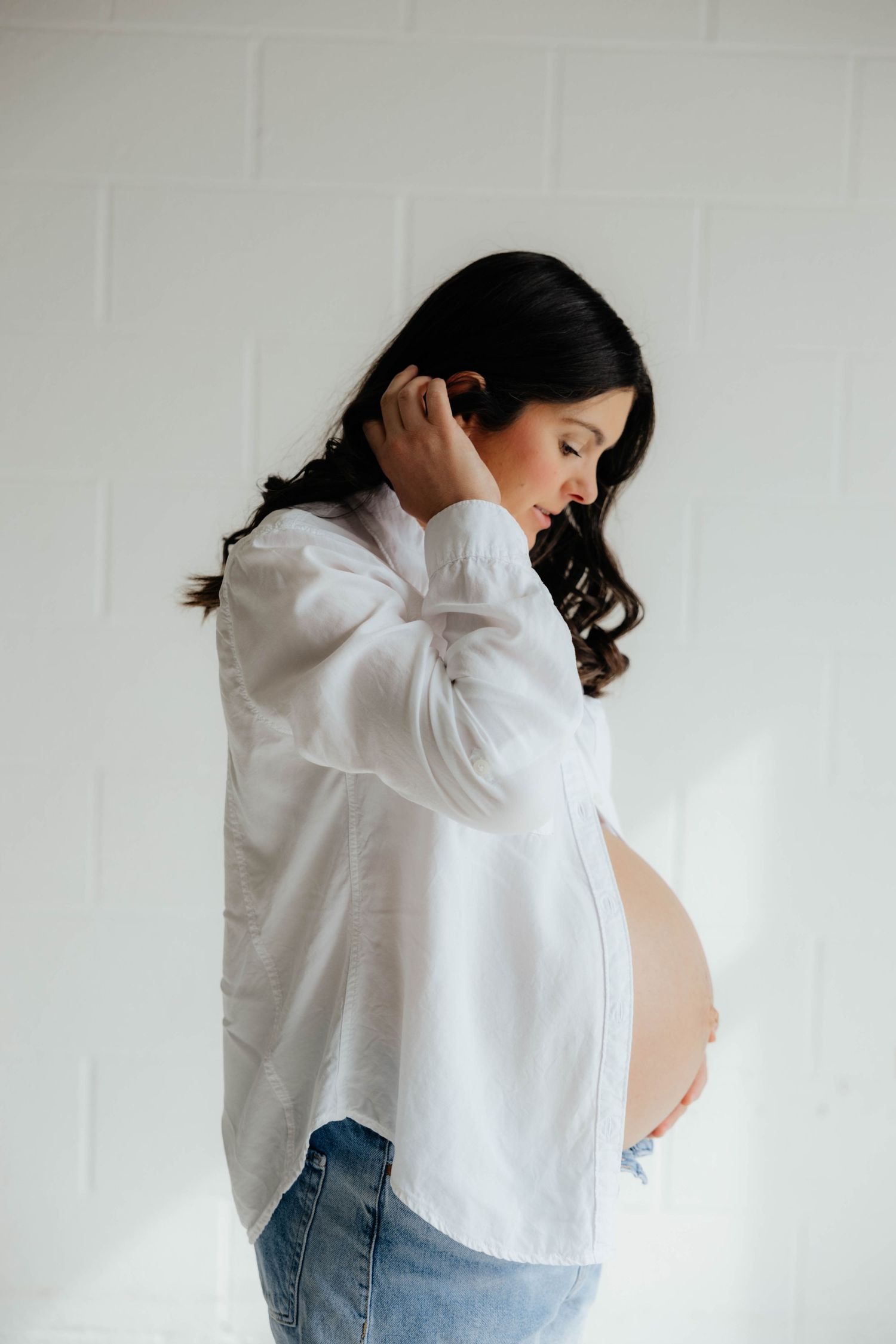 A series of artistic maternity photos showing a woman in a white shirt against a light background.