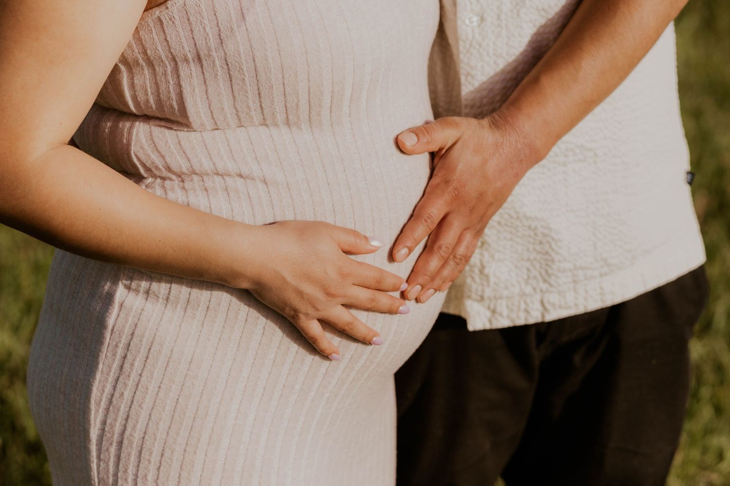 Close-up shots of hands tenderly cradling a pregnant belly in soft lighting.