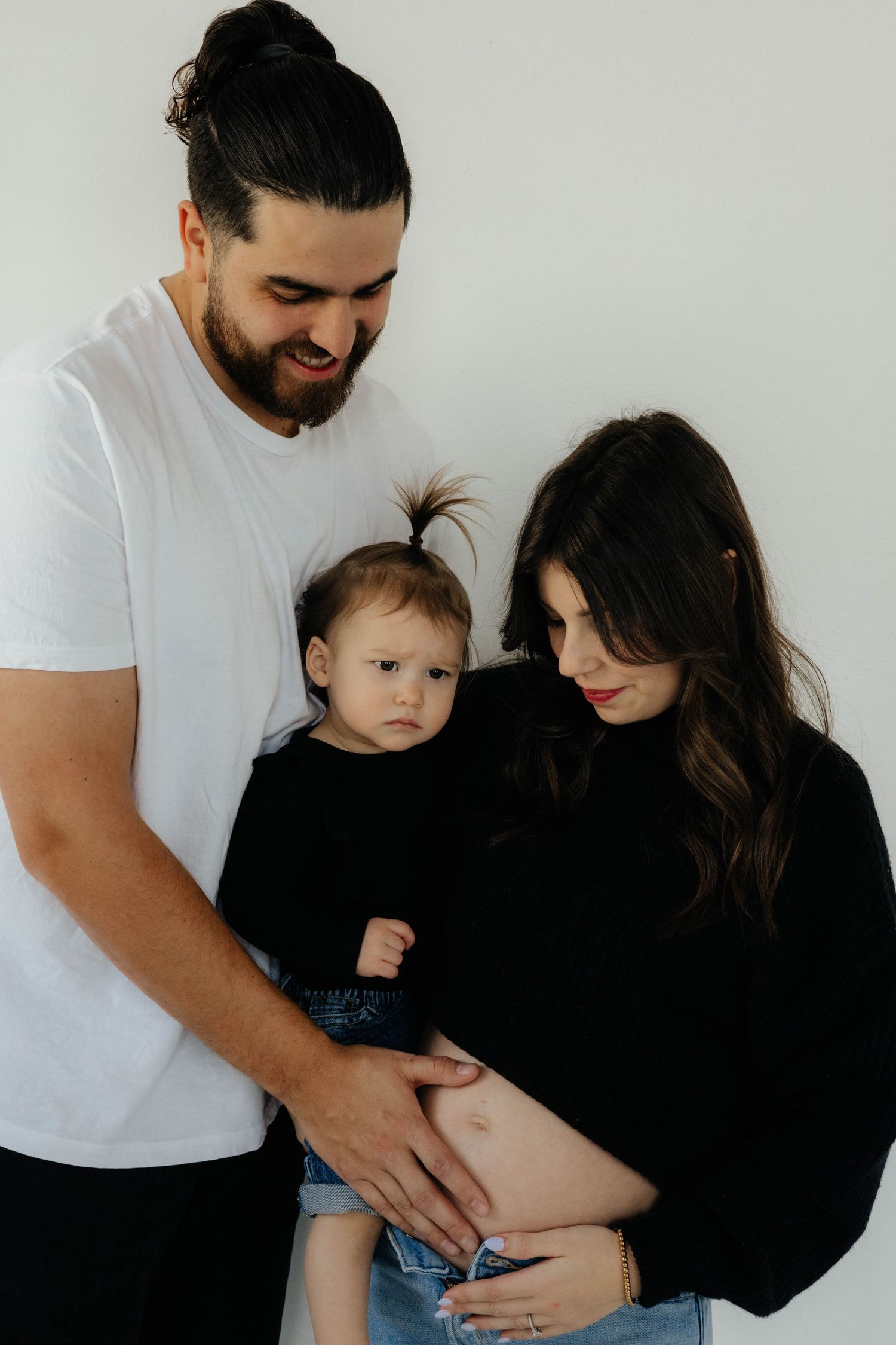 A family shares intimate moments together against a white background.