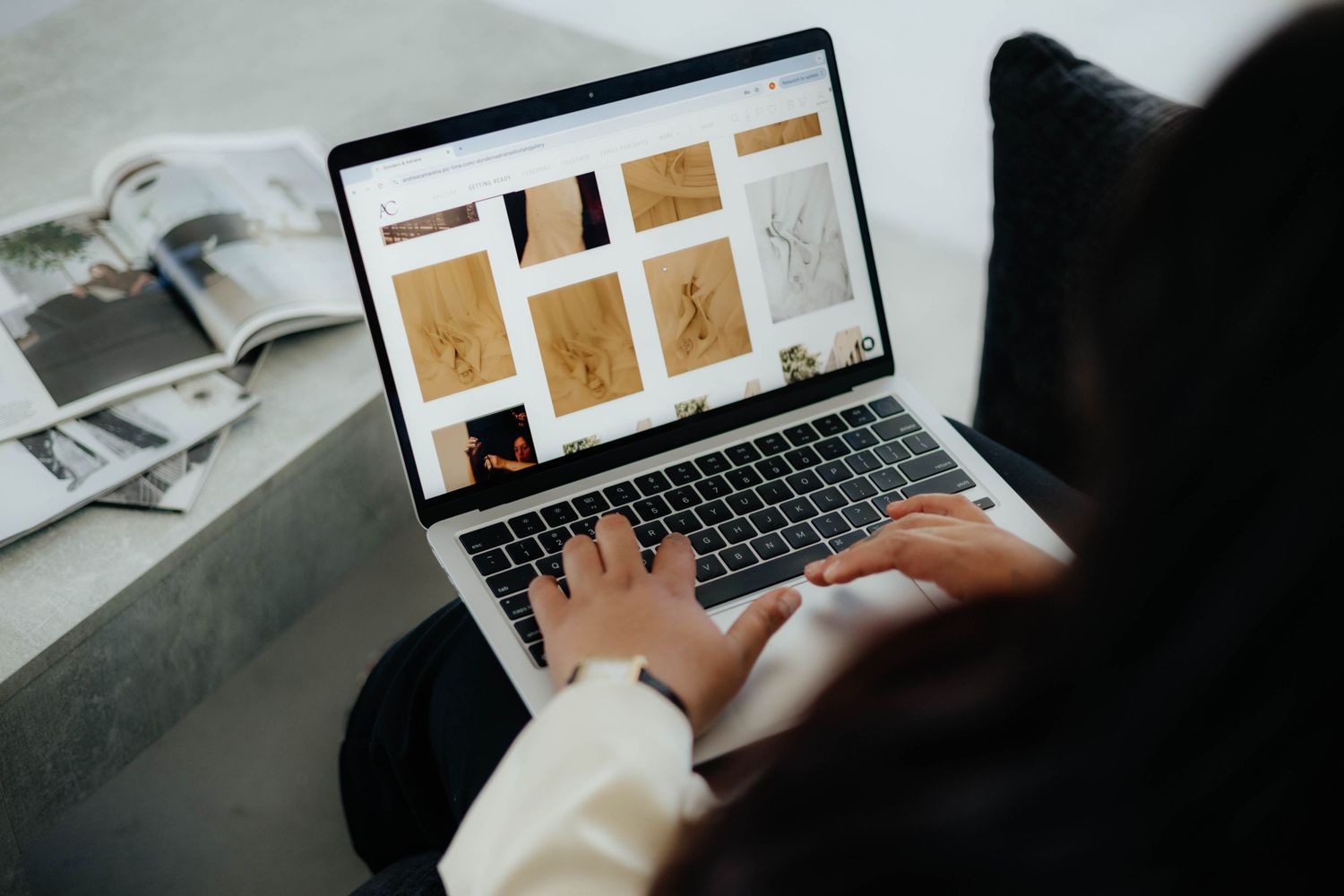 Person typing on laptop displaying brown and beige website design mockups.
