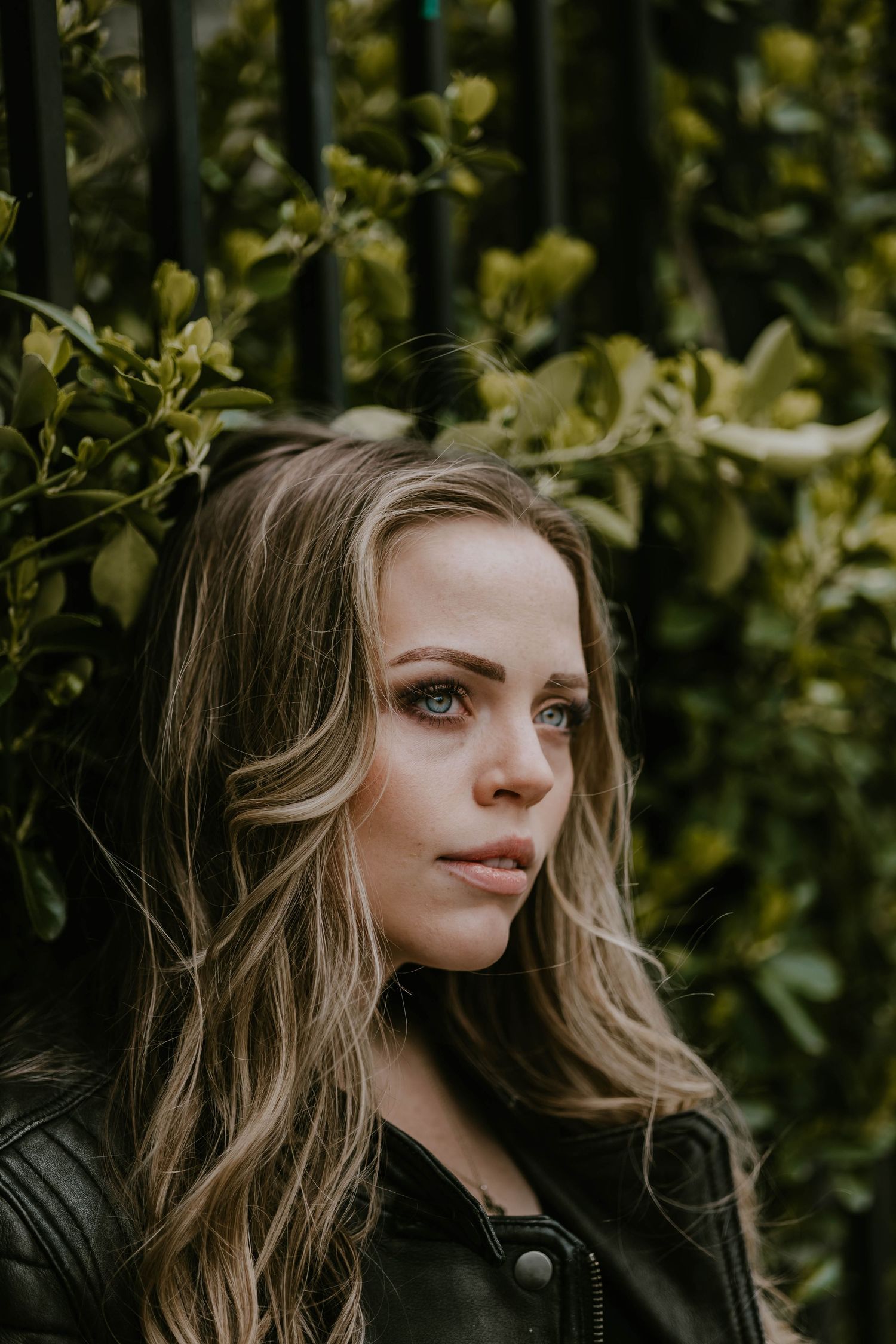 Artistic portrait series showing windswept hair against natural foliage background.