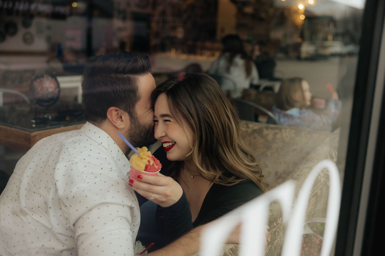 Romantic couple embracing by a window with soft natural lighting.