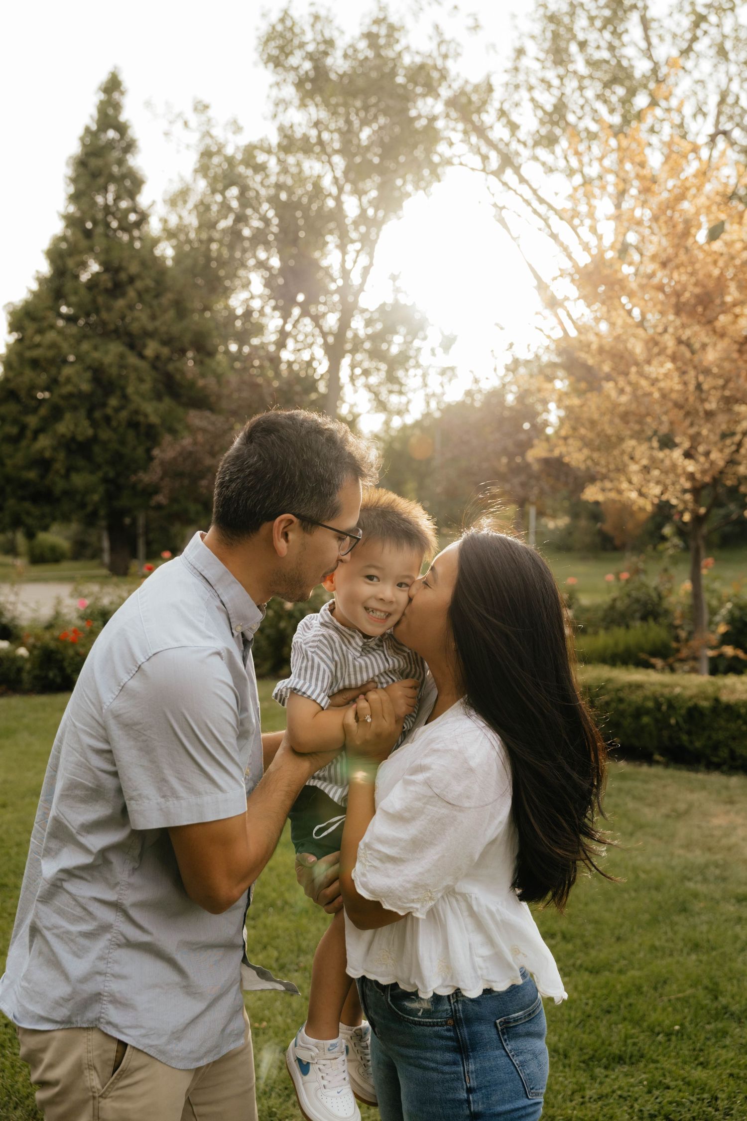 A loving family moment captured in golden sunlight at a park.
