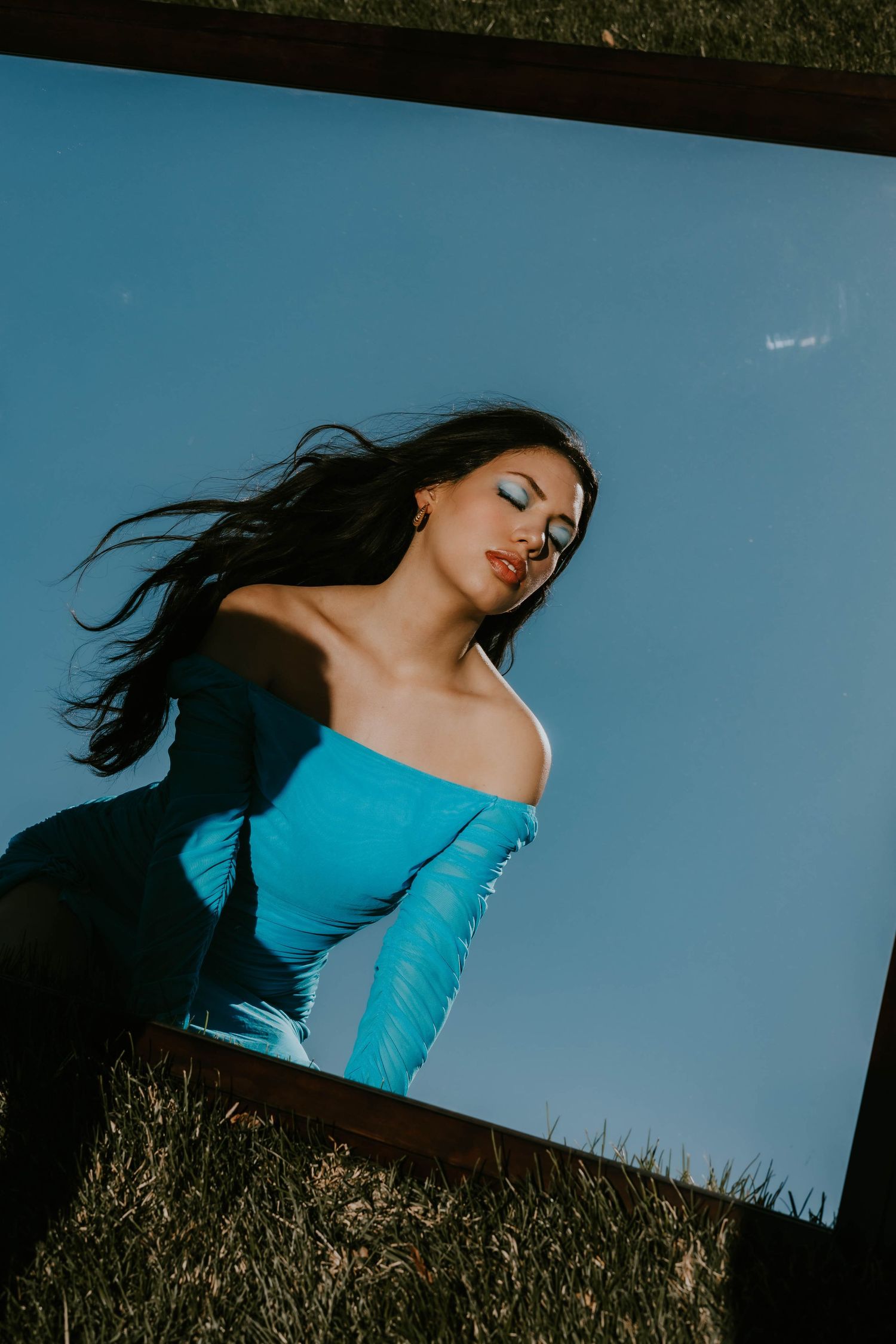 Dramatic silhouette in turquoise top against vibrant blue sky.