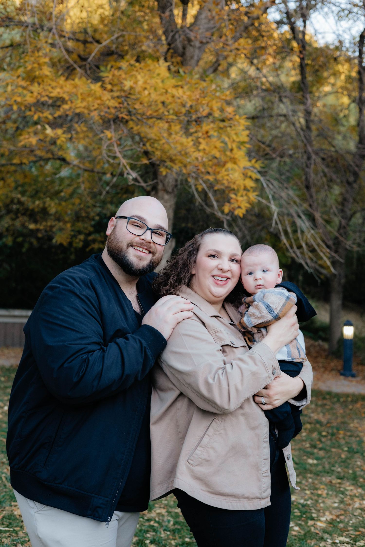 A joyful autumn family portrait with golden leaves in the background.