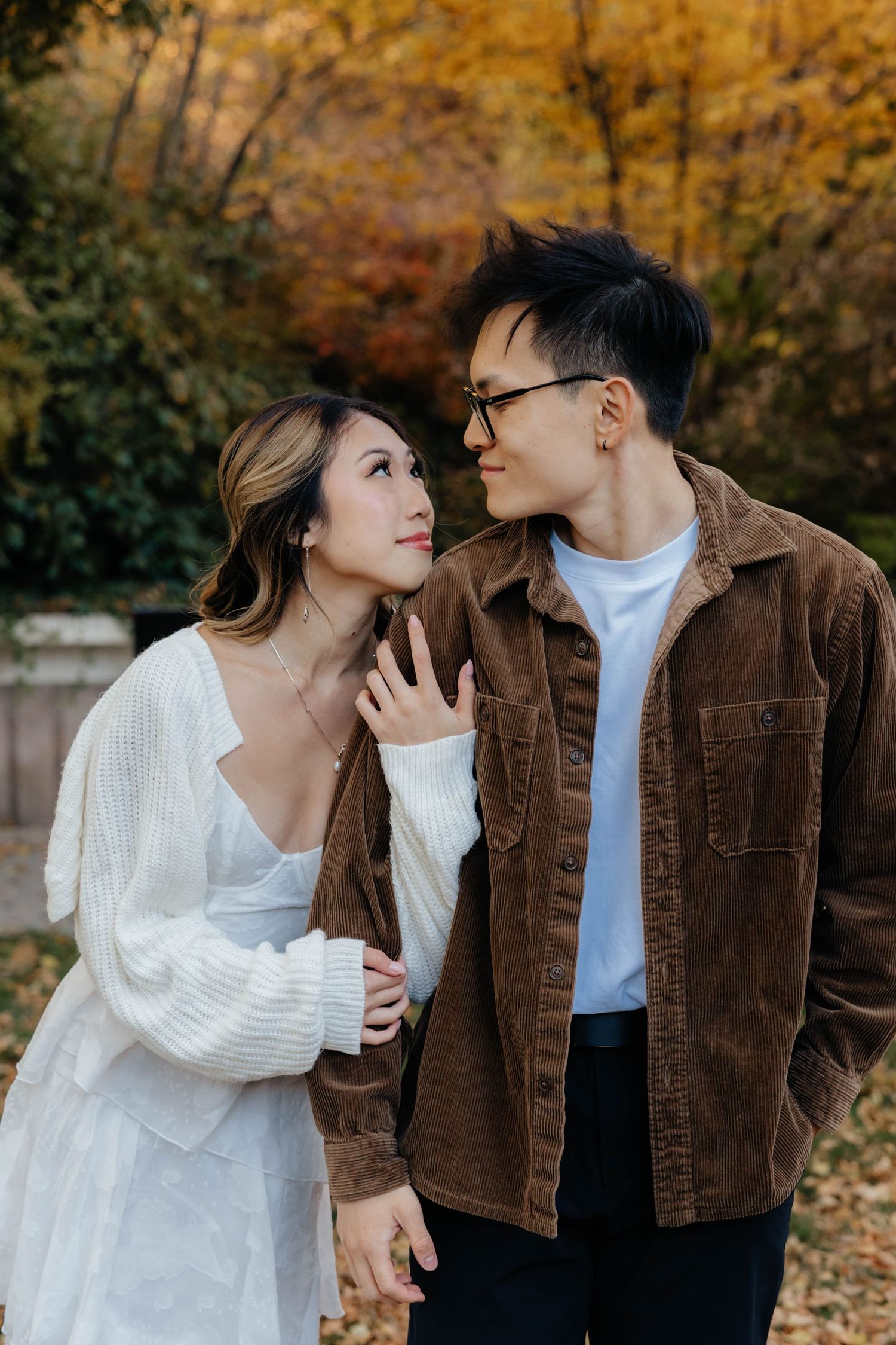 Romantic autumn photoshoot with couple in white sweater and brown corduroy jacket.