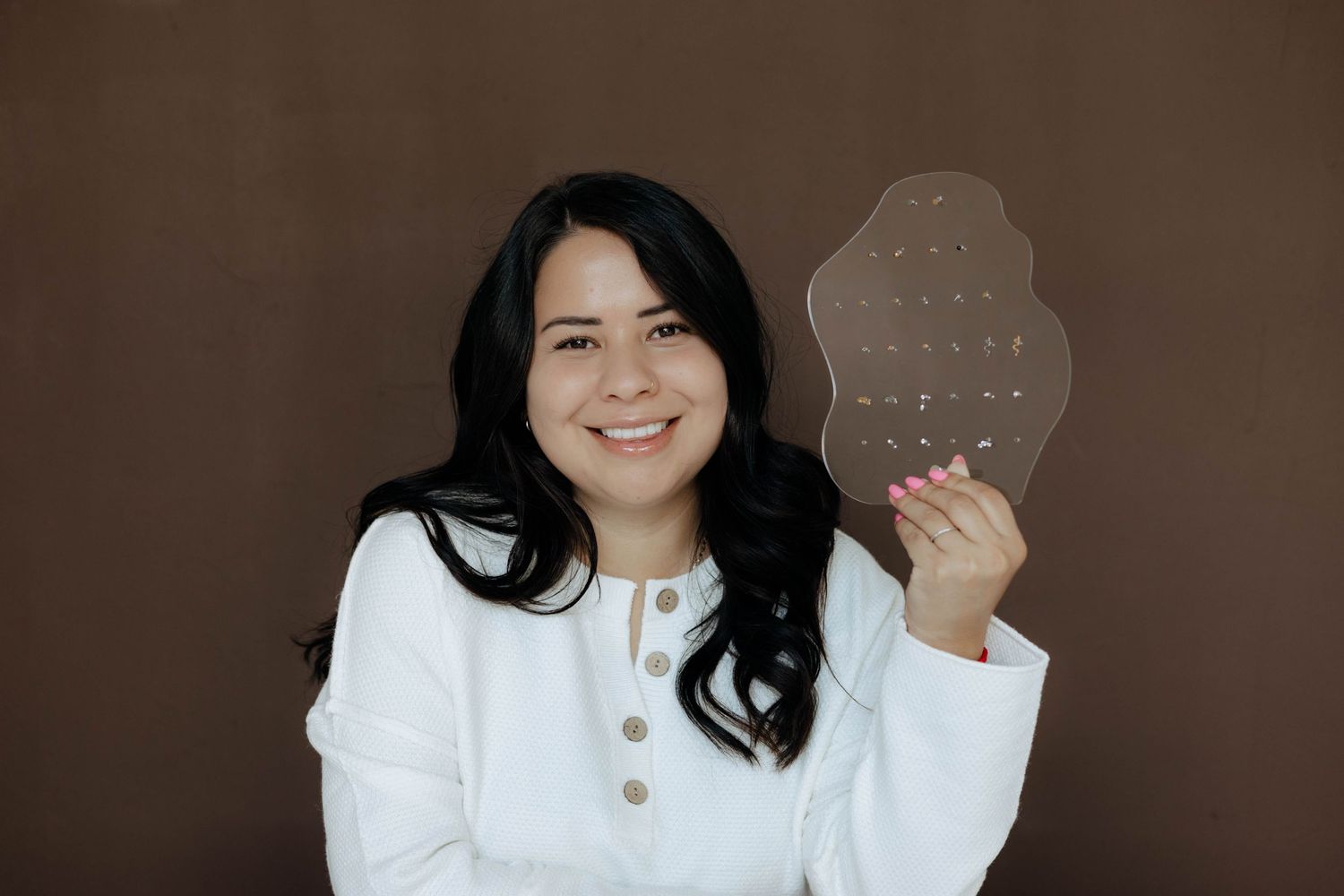 Person in white sweater posing with hexagonal shaped object.