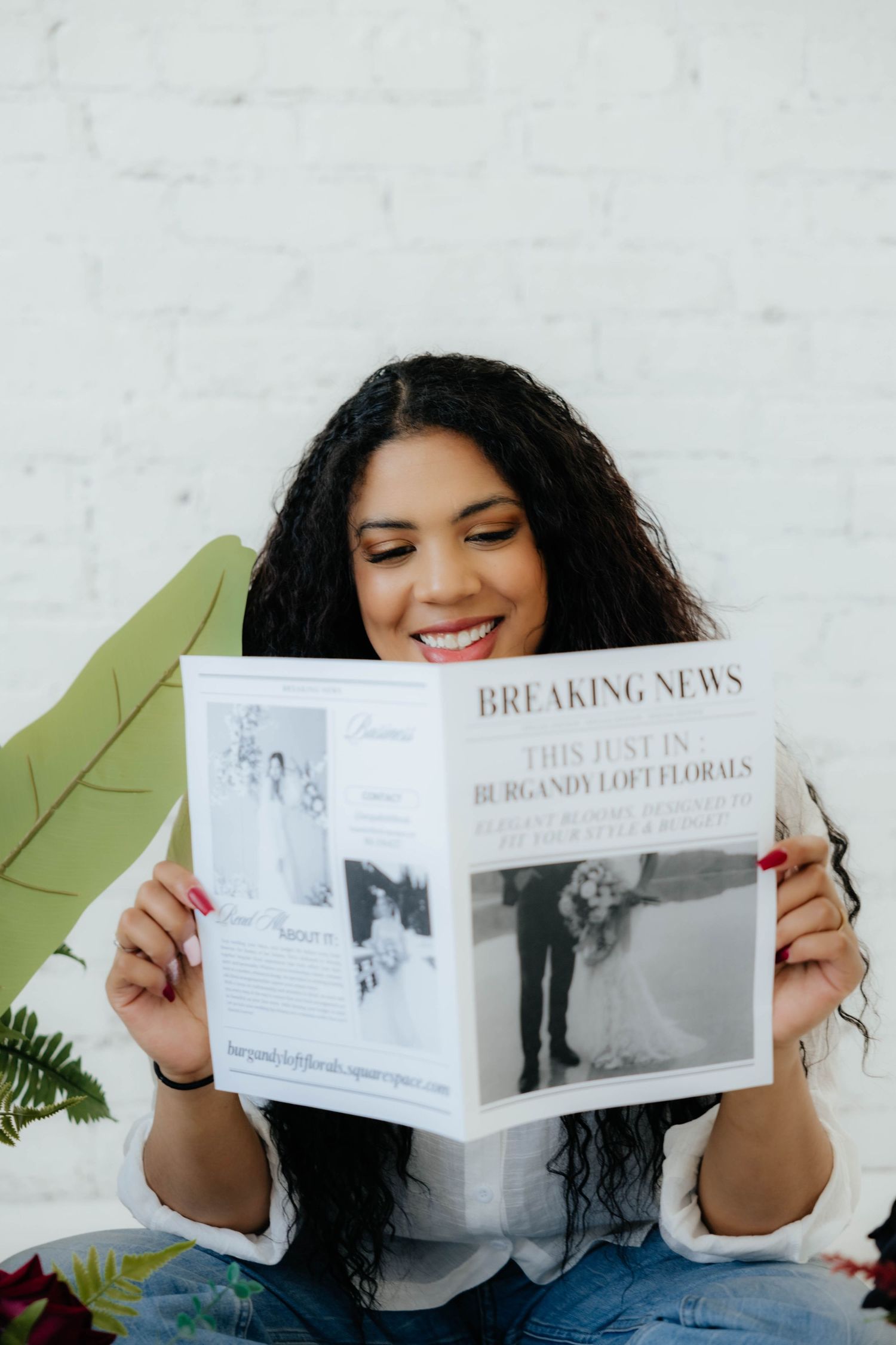 Someone reading and displaying a printed publication titled 'Breaking News' against a white wall.