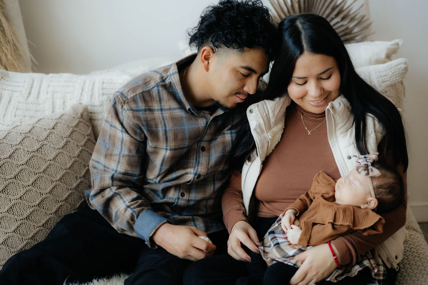New parents sharing tender moment with newborn baby on cozy bed.