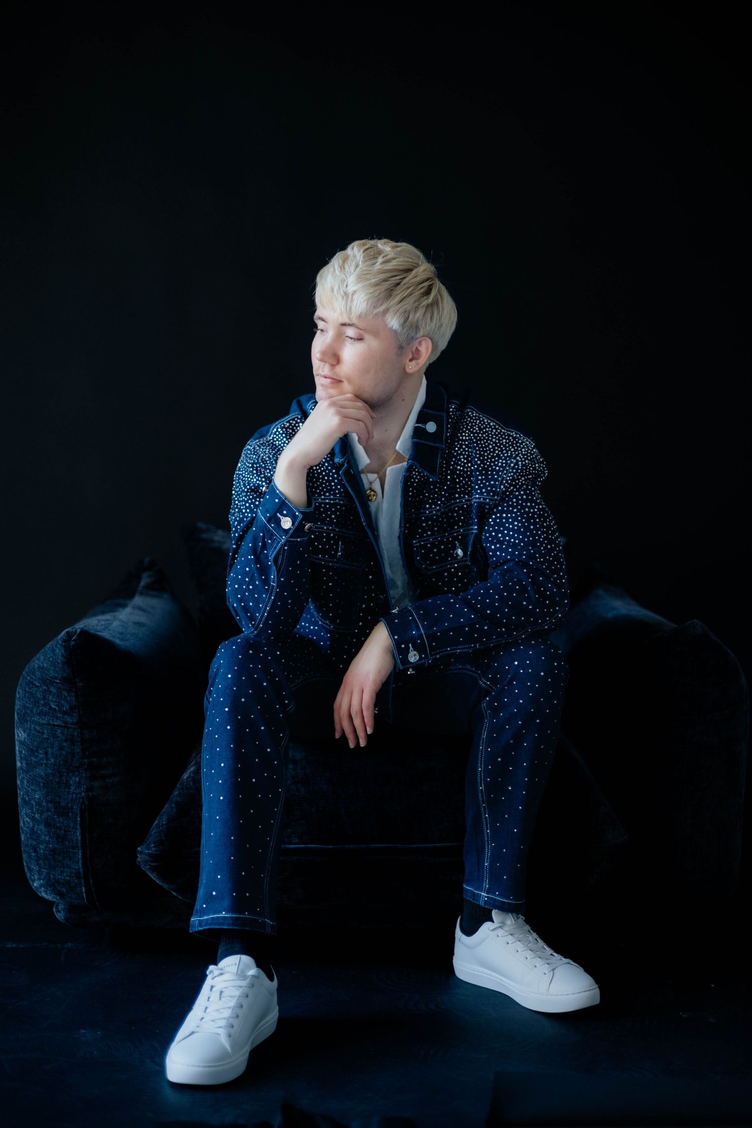 Artistic portrait in polka dot outfit against dark background with white sneakers.