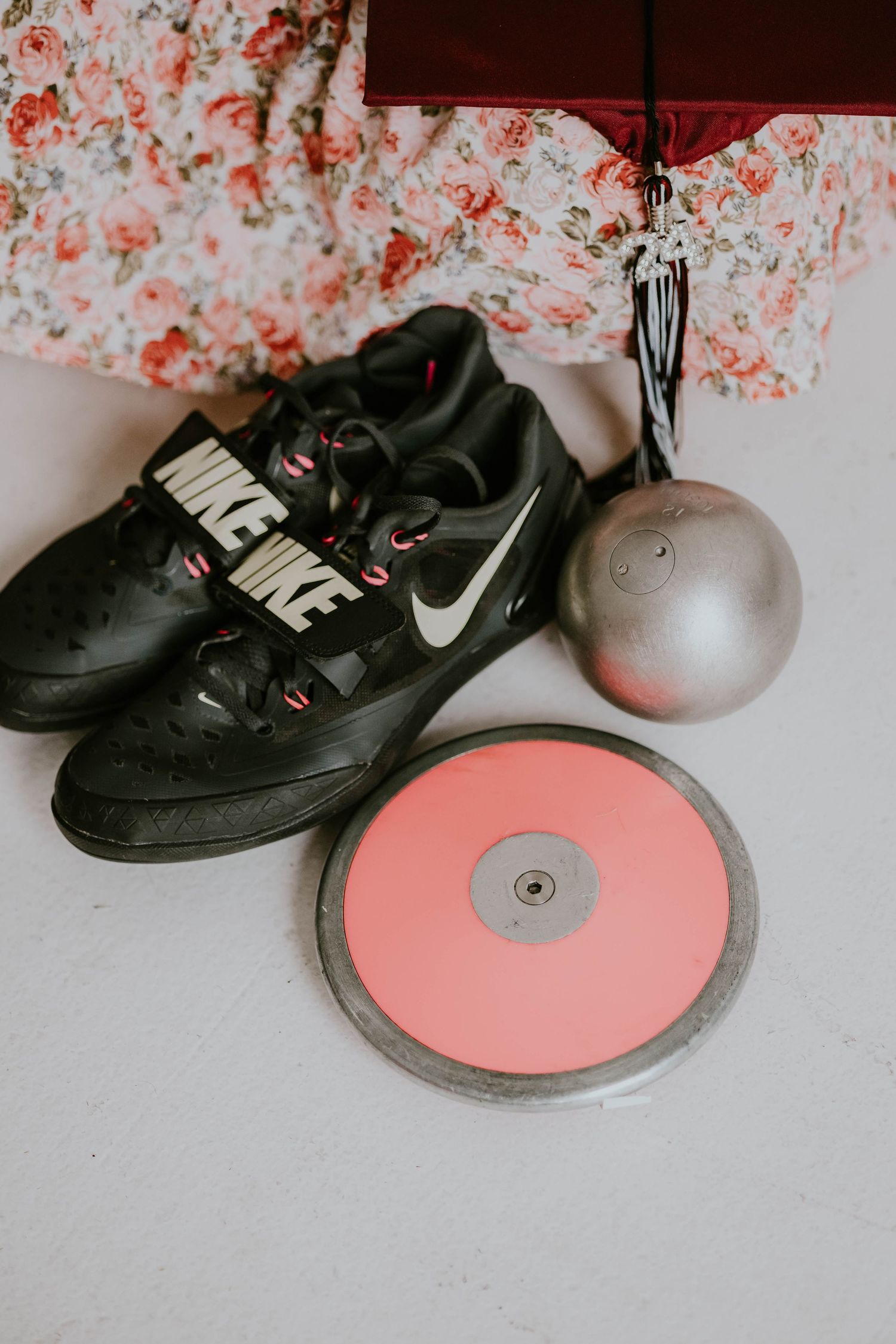 Still life of black Nike shoes with pink discus weights in artistic composition.