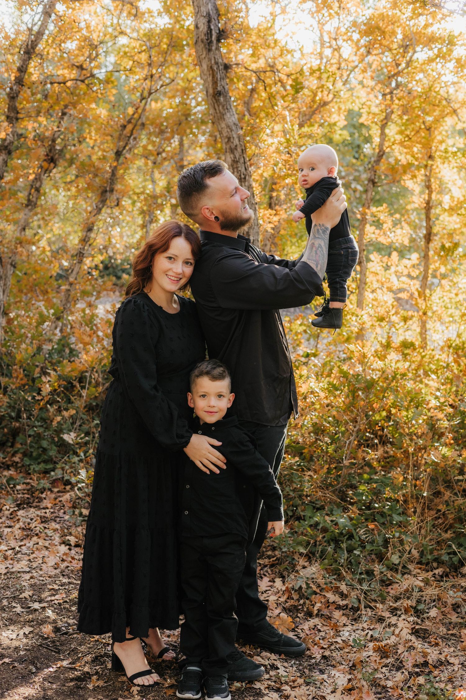 A playful family photo session in a park with golden autumn foliage.