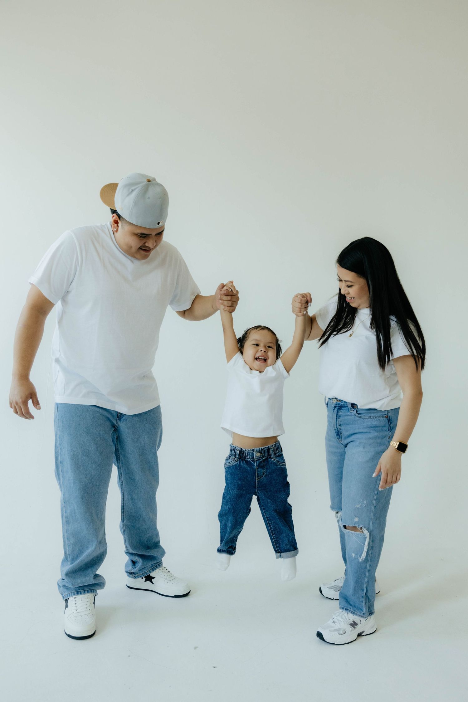 A family in matching white shirts and jeans dances together against a white background.