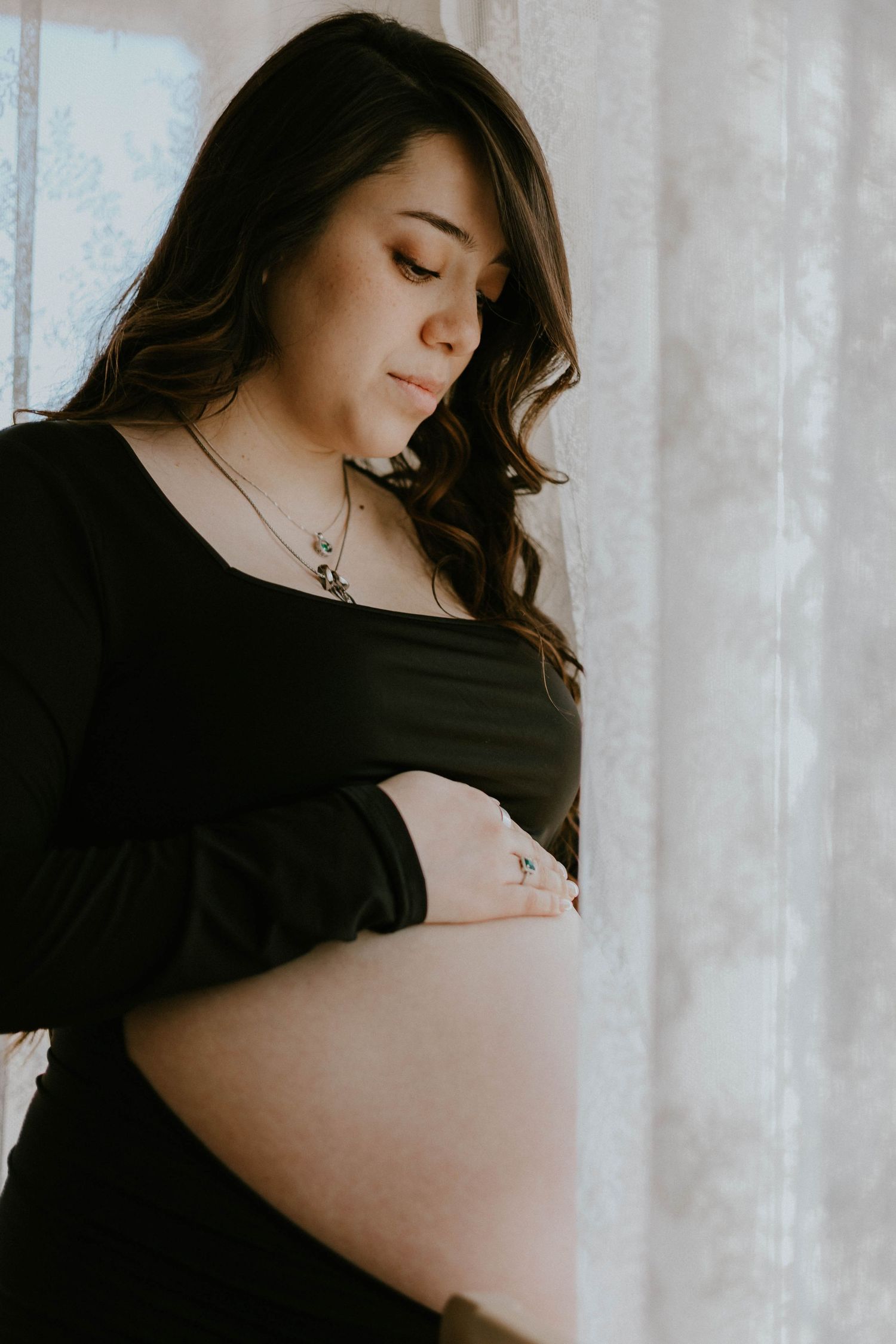 Dramatic black and white maternity portraits with sheer curtain backdrop.