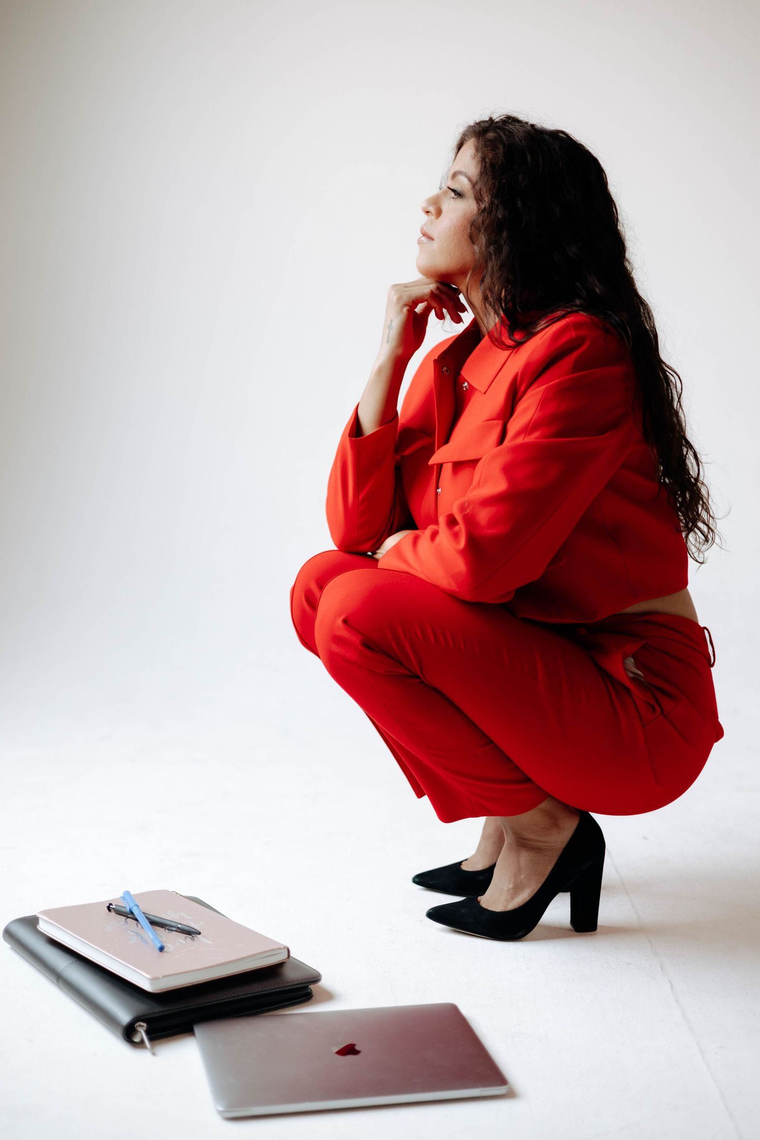 Person in bright red outfit posing with laptop against white background.