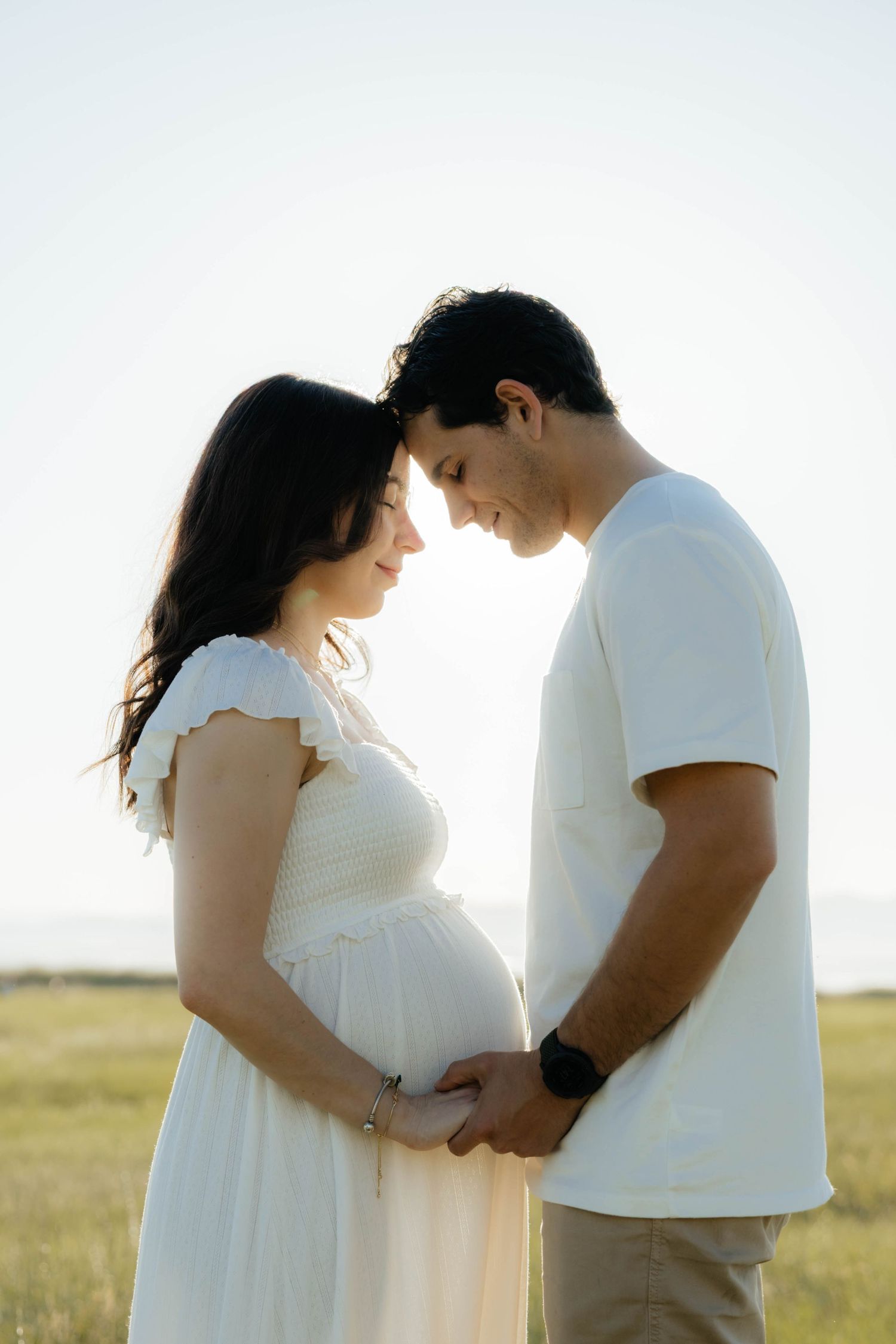 Romantic maternity photos taken at golden hour showing tender moments between expectant parents.